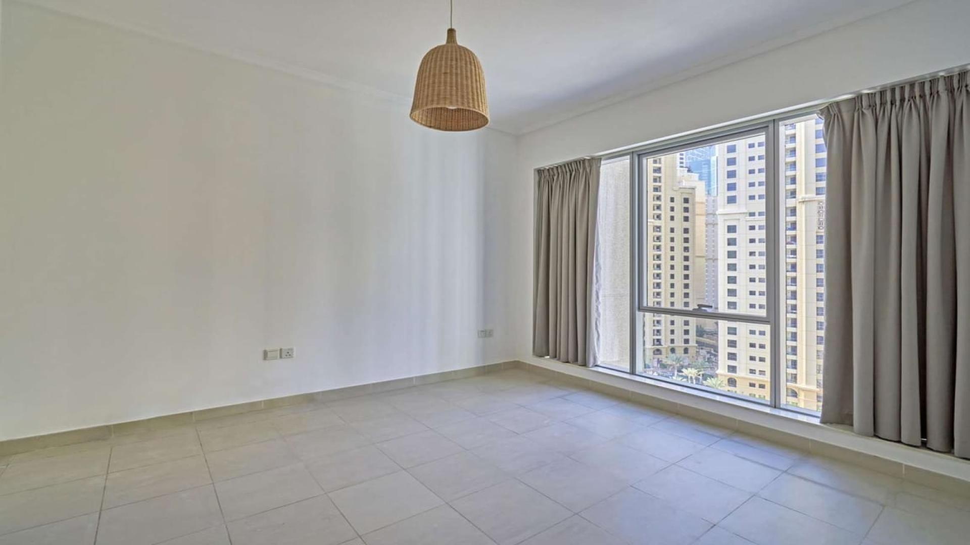 "Bright living area in 2-bedroom apartment with marina views, Dubai Marina, for rent.",Empty room with large window and city views in Dubai Marina apartment for rent