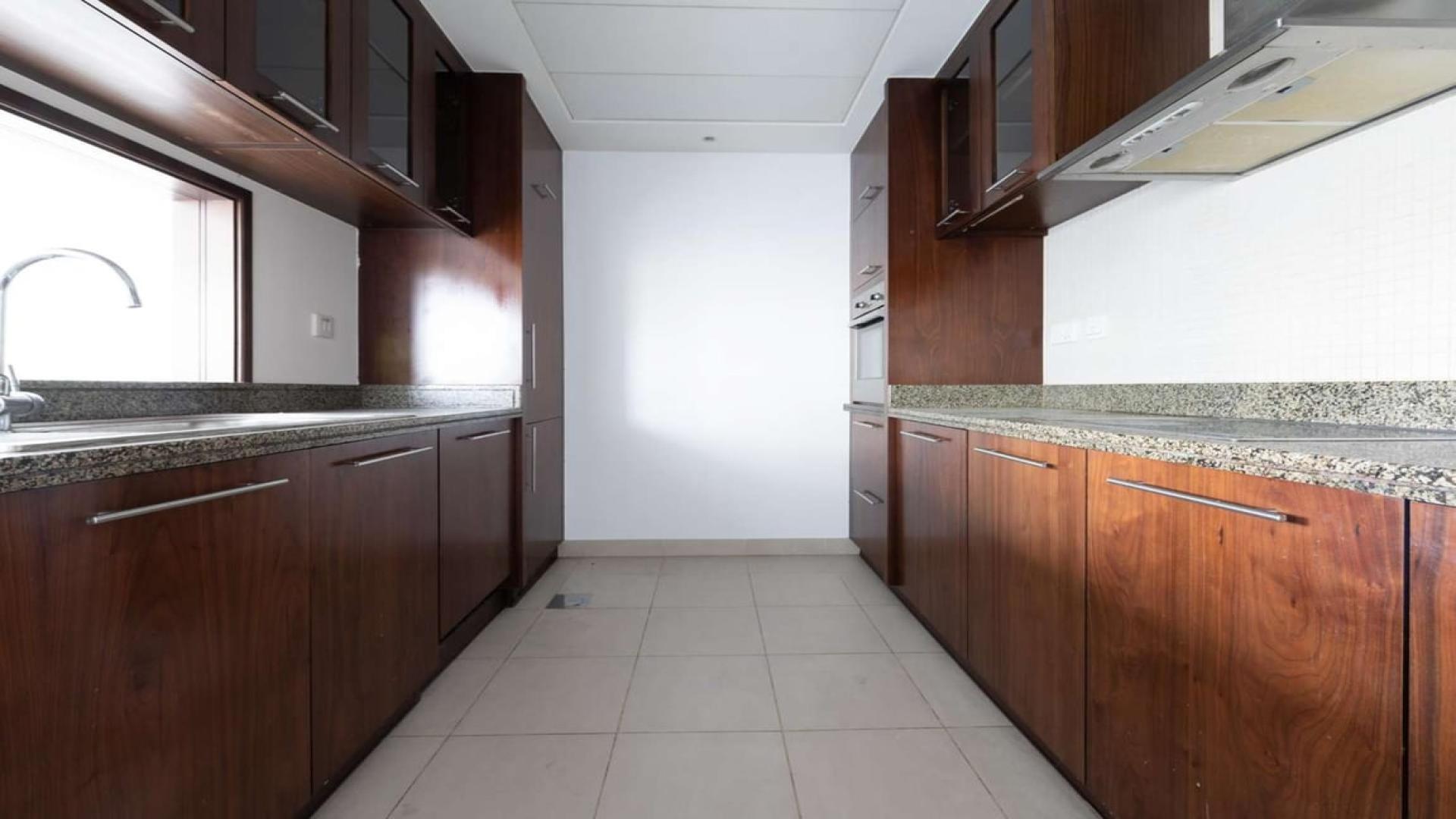 "Marina Promenade apartment with panoramic window view of Dubai Marina skyline and waterfront.",Modern kitchen in Marina Promenade apartment, Dubai Marina. Granite countertops, wooden cabinets