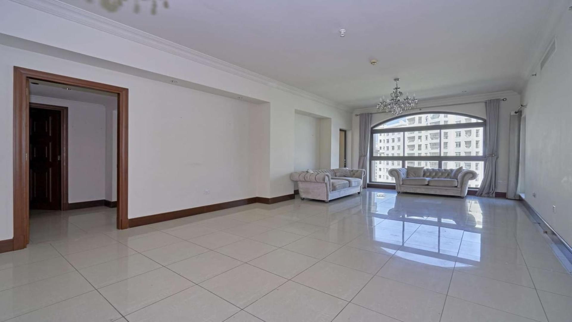 Alt text: "View of Shoreline Apartments in Palm Jumeirah, Dubai, surrounded by lush greenery.",Spacious living room in 2-bedroom apartment, Shoreline, Palm Jumeirah, with large windows