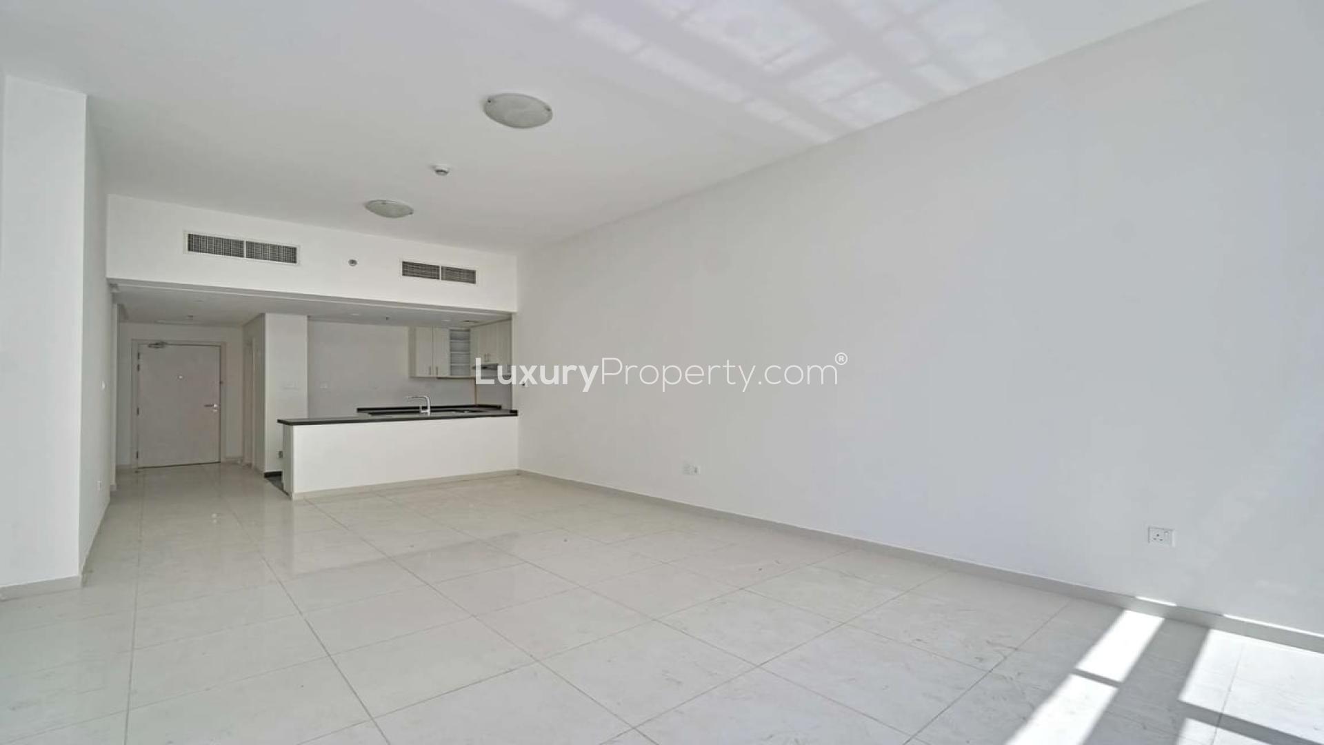 Empty living room with large windows in Damac Hills apartment, Golf Vista community