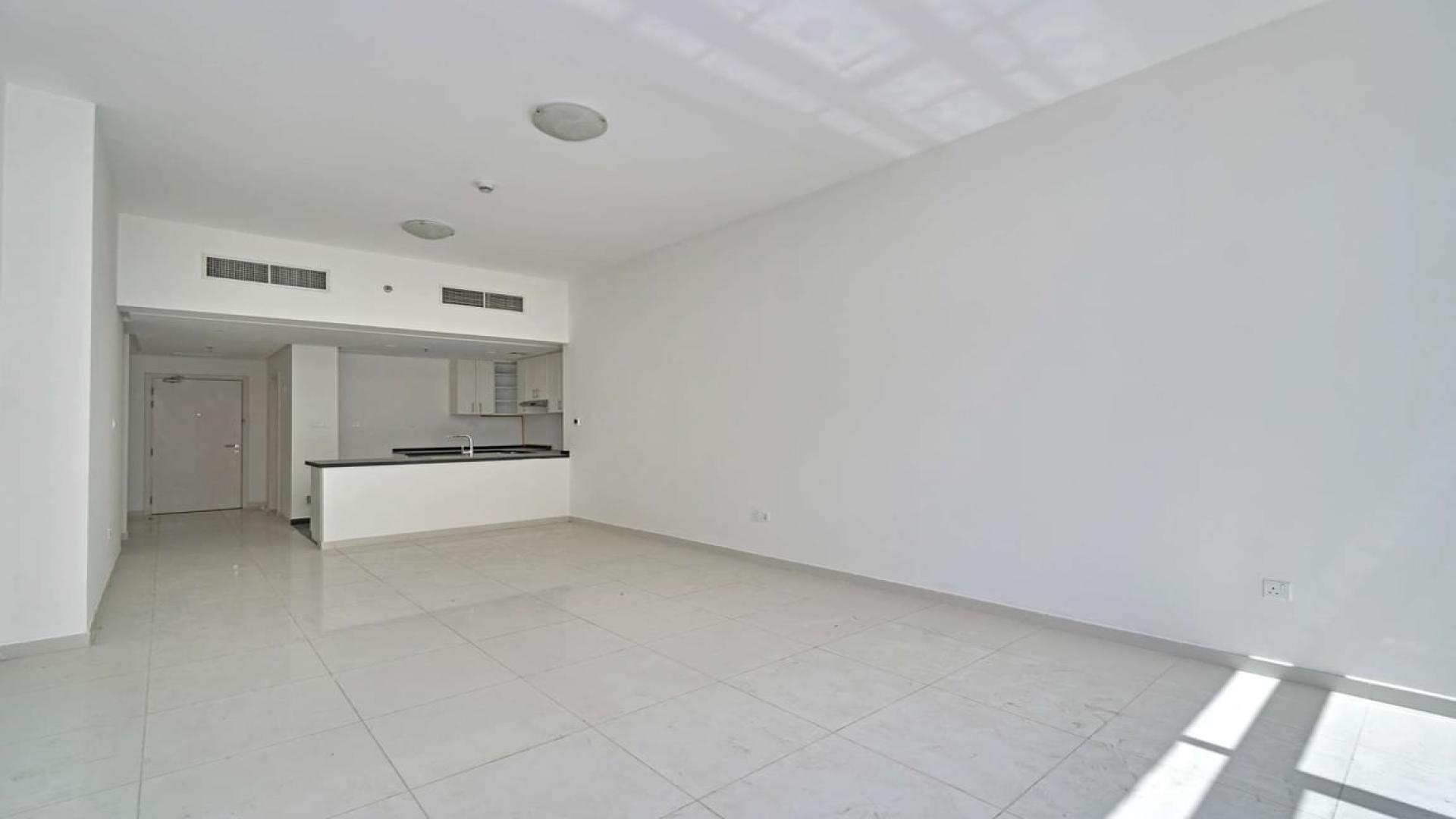 Empty living room with large windows in Damac Hills apartment, Golf Vista community