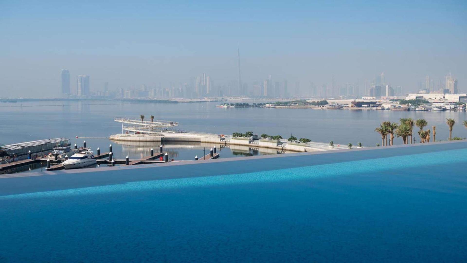 Infinity pool overlooking Dubai Creek Harbour skyline from apartment balcony