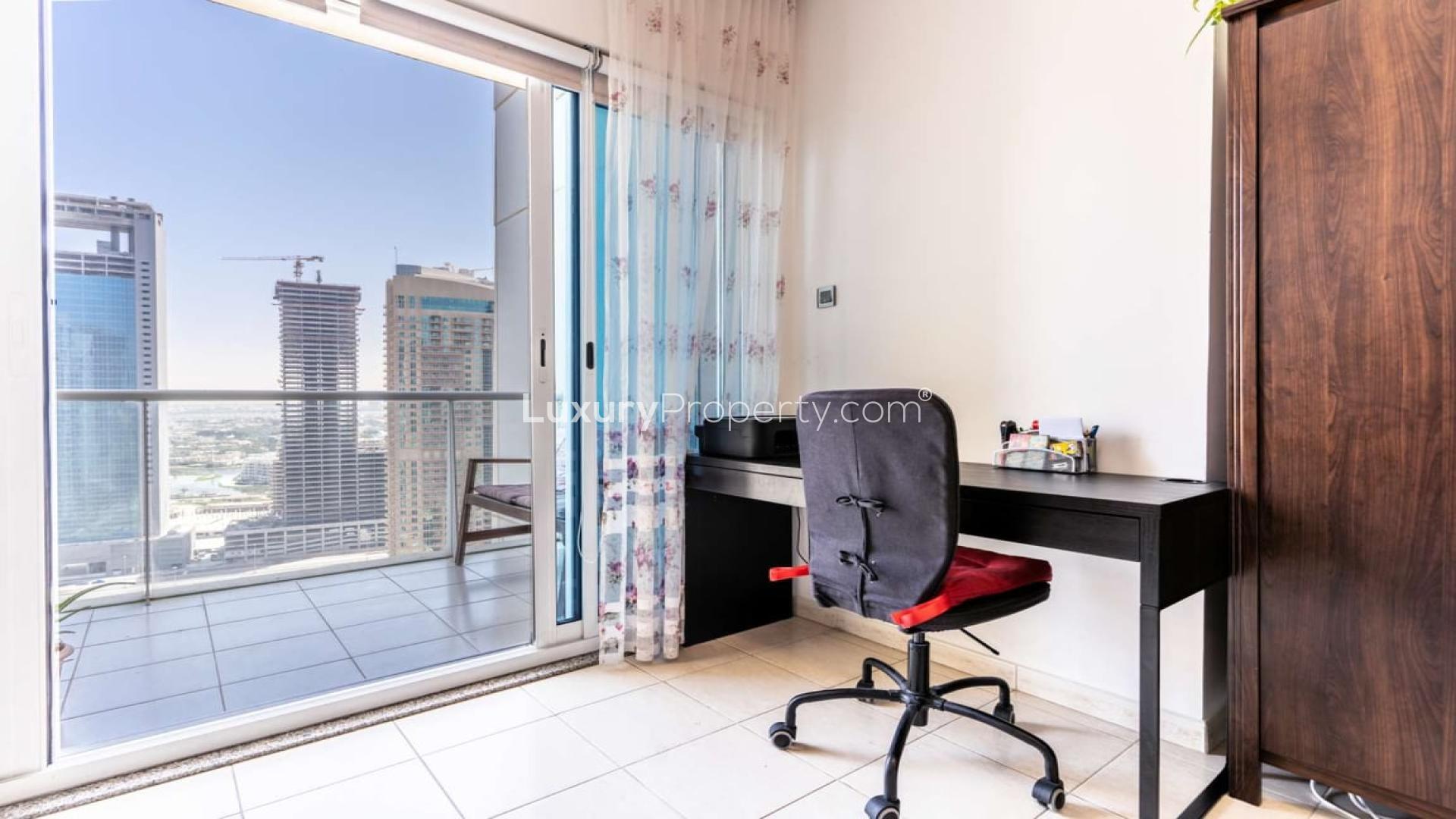 Spacious JLT Lake View apartment balcony with cityscape, greenery, and seating area