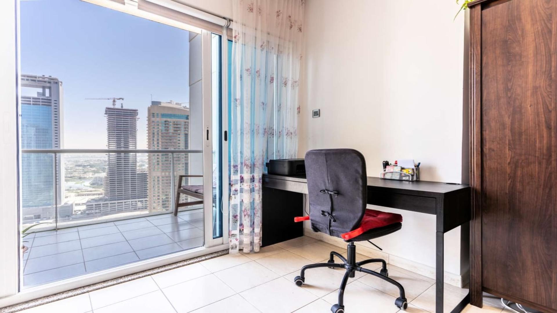 Spacious JLT Lake View apartment balcony with cityscape, greenery, and seating area