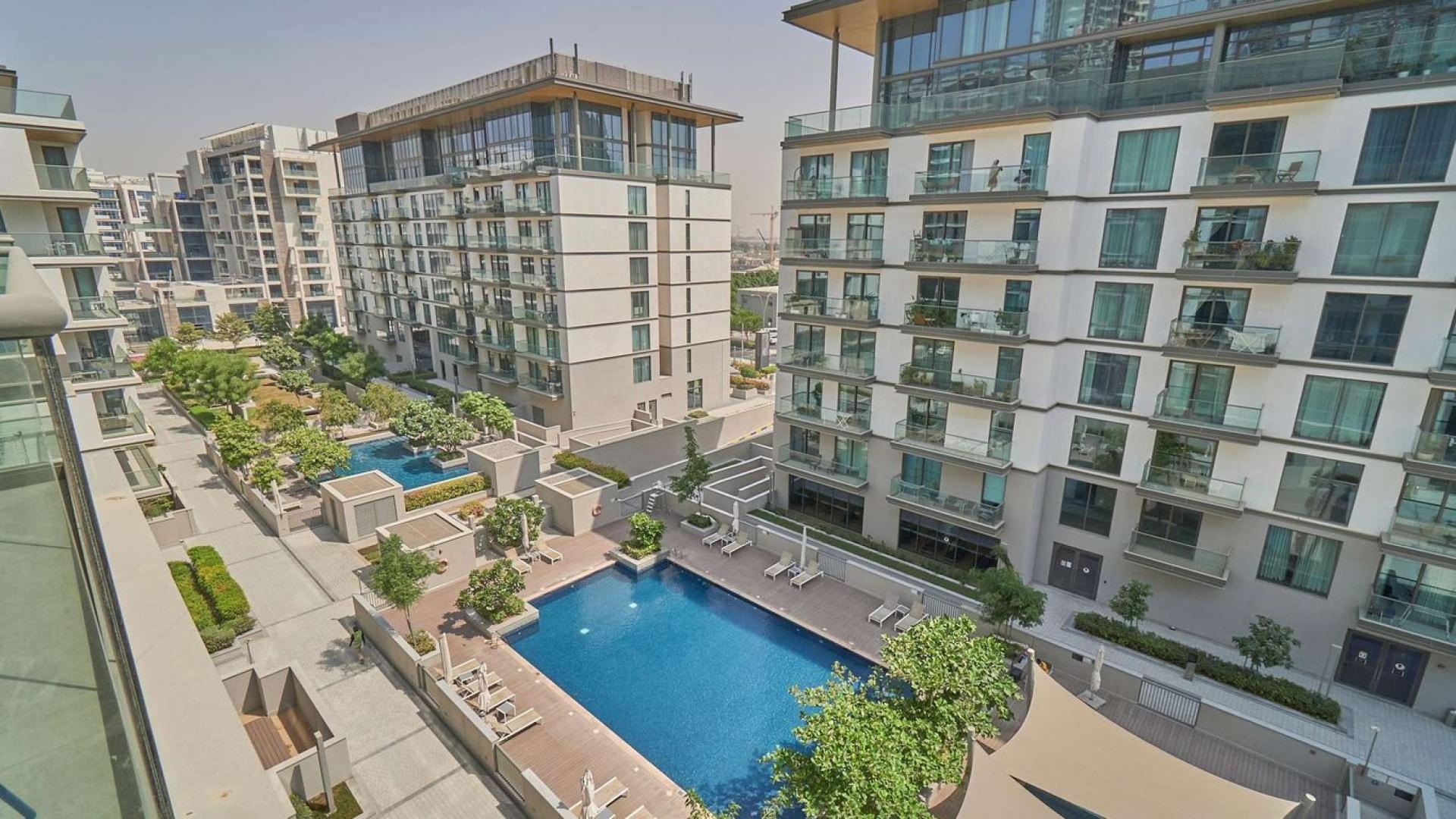 Exterior view of Sobha Hartland apartment buildings with swimming pool and landscaped gardens