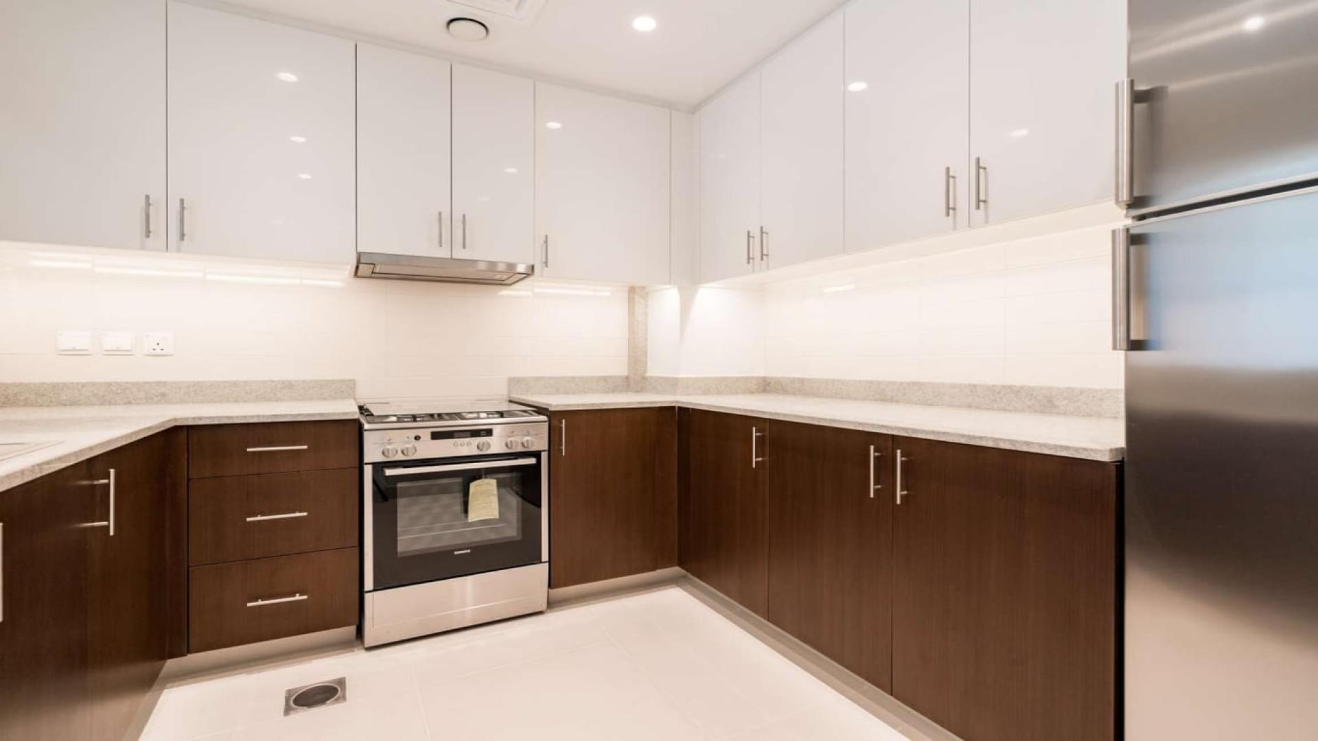 Modern apartment building in Downtown Dubai's BLVD Crescent, surrounded by palm trees and shops