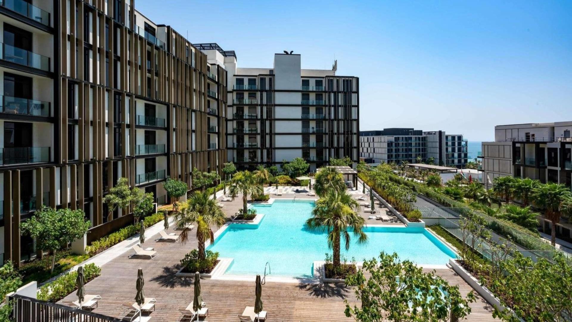 Modern apartment complex with pool view at Caesars Bluewaters Dubai, available for rent