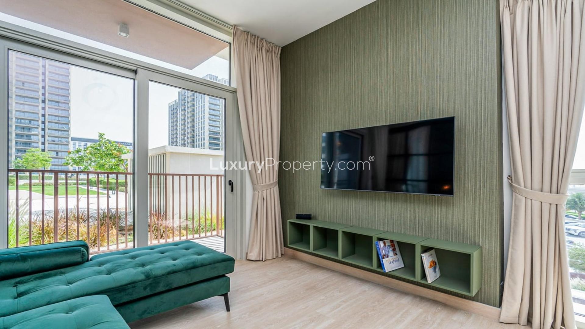 Modern living room in Dubai Hills Estate apartment with green sofa and wall-mounted TV