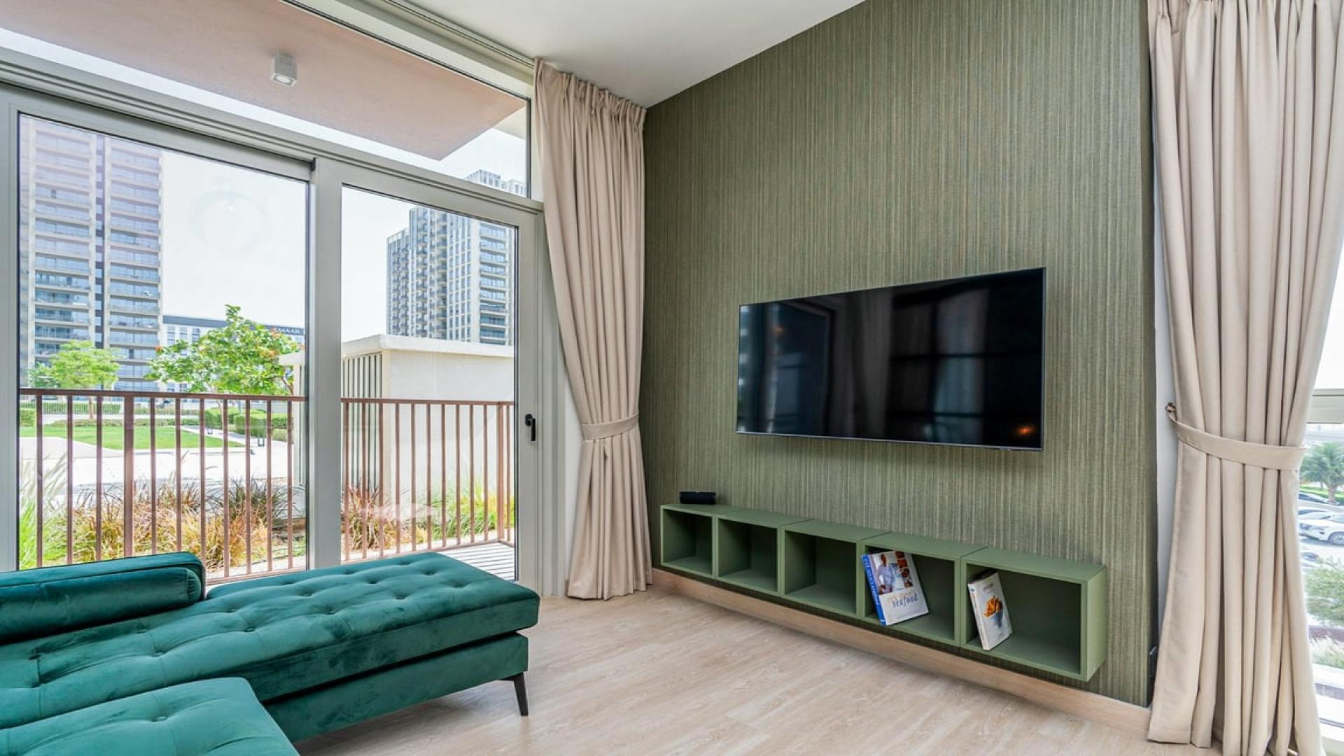 Modern living room in Dubai Hills Estate apartment with green sofa and wall-mounted TV