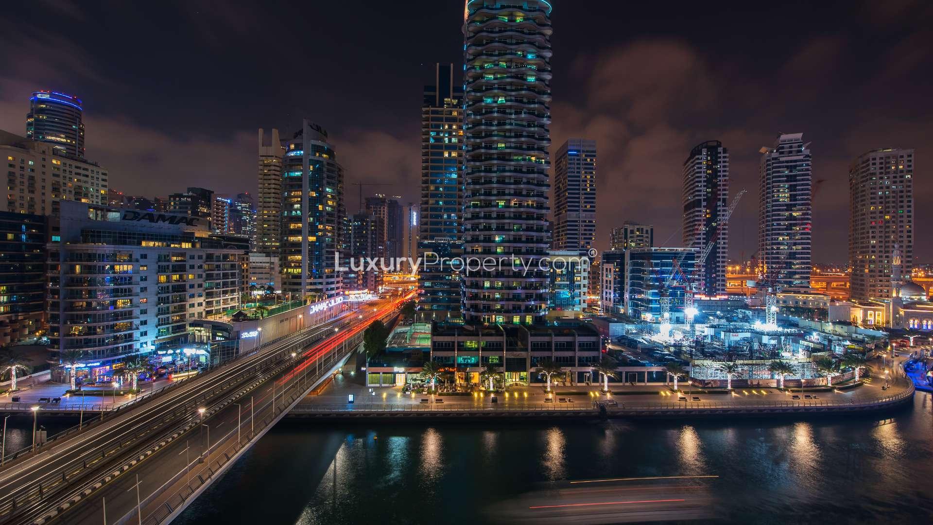 Night view of JBR apartment pool with cityscape and illuminated palm trees