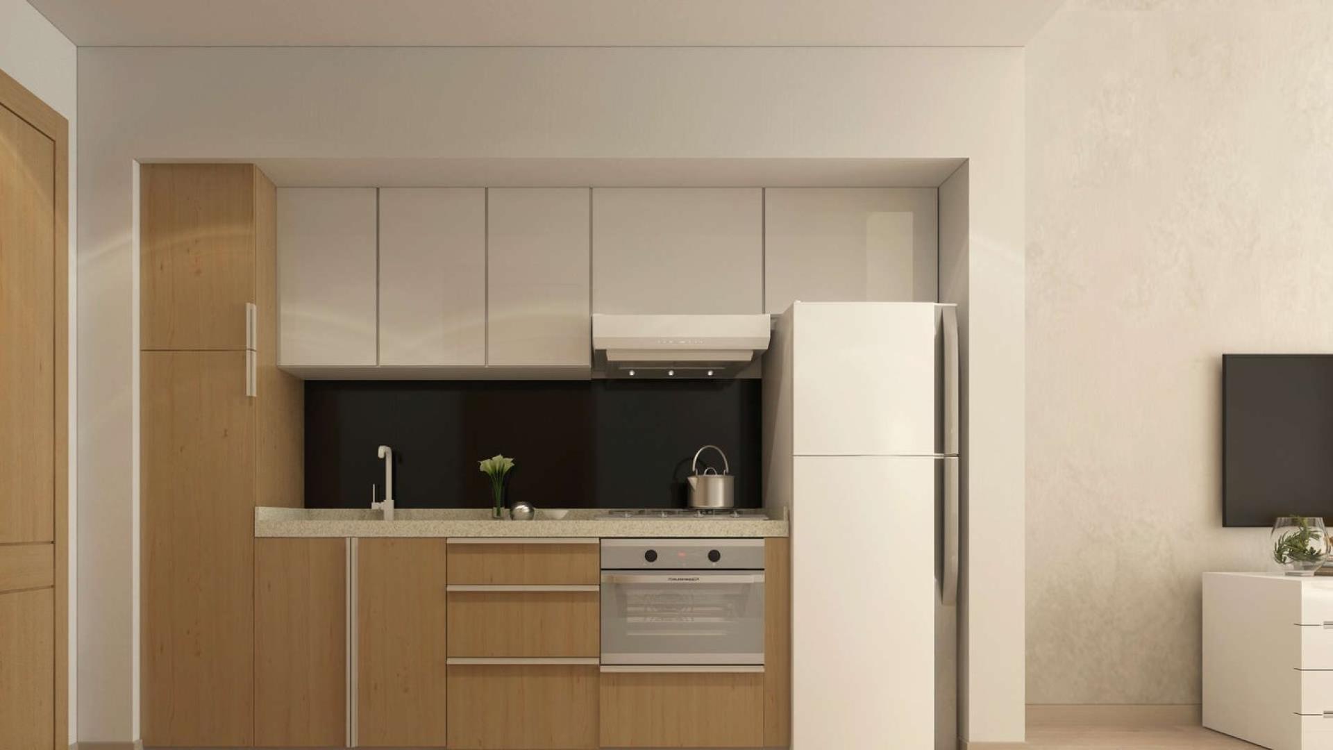 Contemporary kitchen in Studio 101 apartment, Dubai Studio City, featuring modern cabinets and appliances
