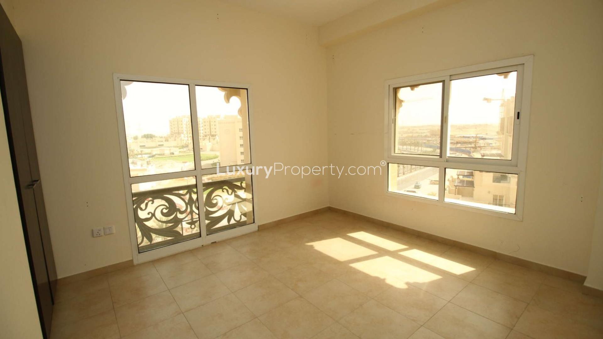Spacious living room in 2-bedroom apartment, Remraam, Dubailand, with large windows and balcony