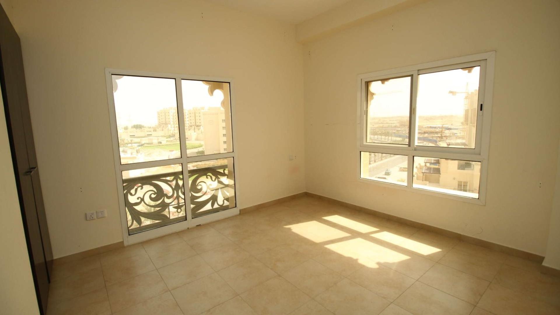 Spacious living room in 2-bedroom apartment, Remraam, Dubailand, with large windows and balcony