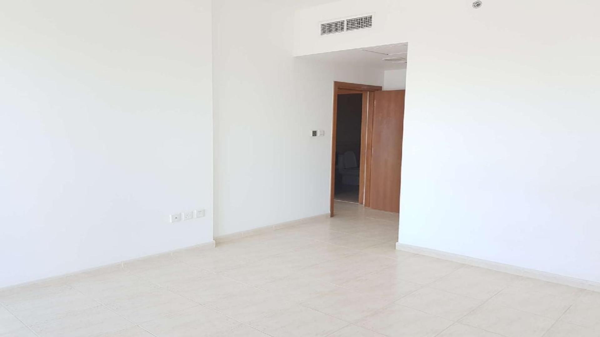 Bright living area with large windows in Skycourt Towers apartment, Dubailand for sale