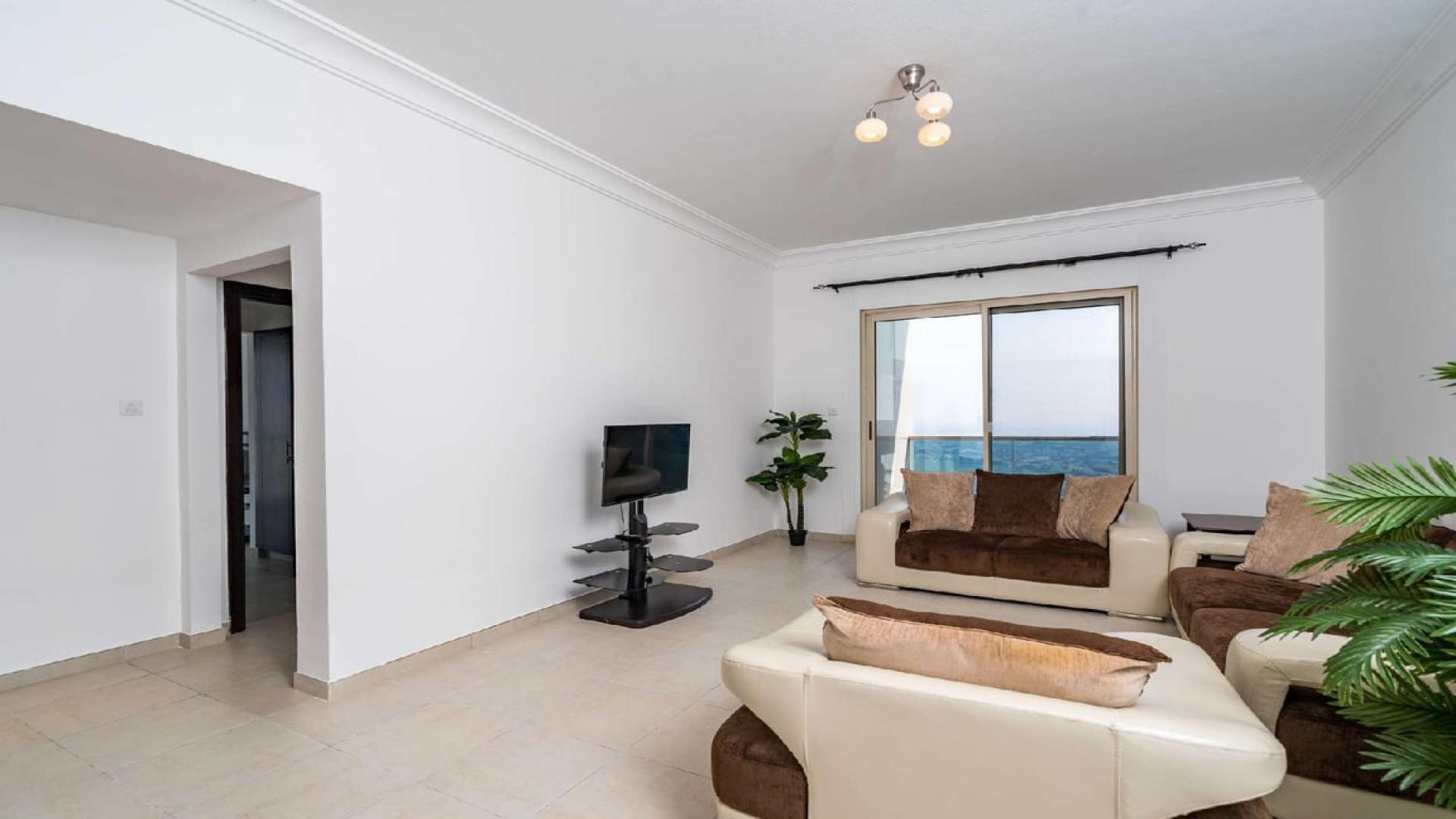 Well-lit living room in spacious JLT apartment, modern furnishings, large window view