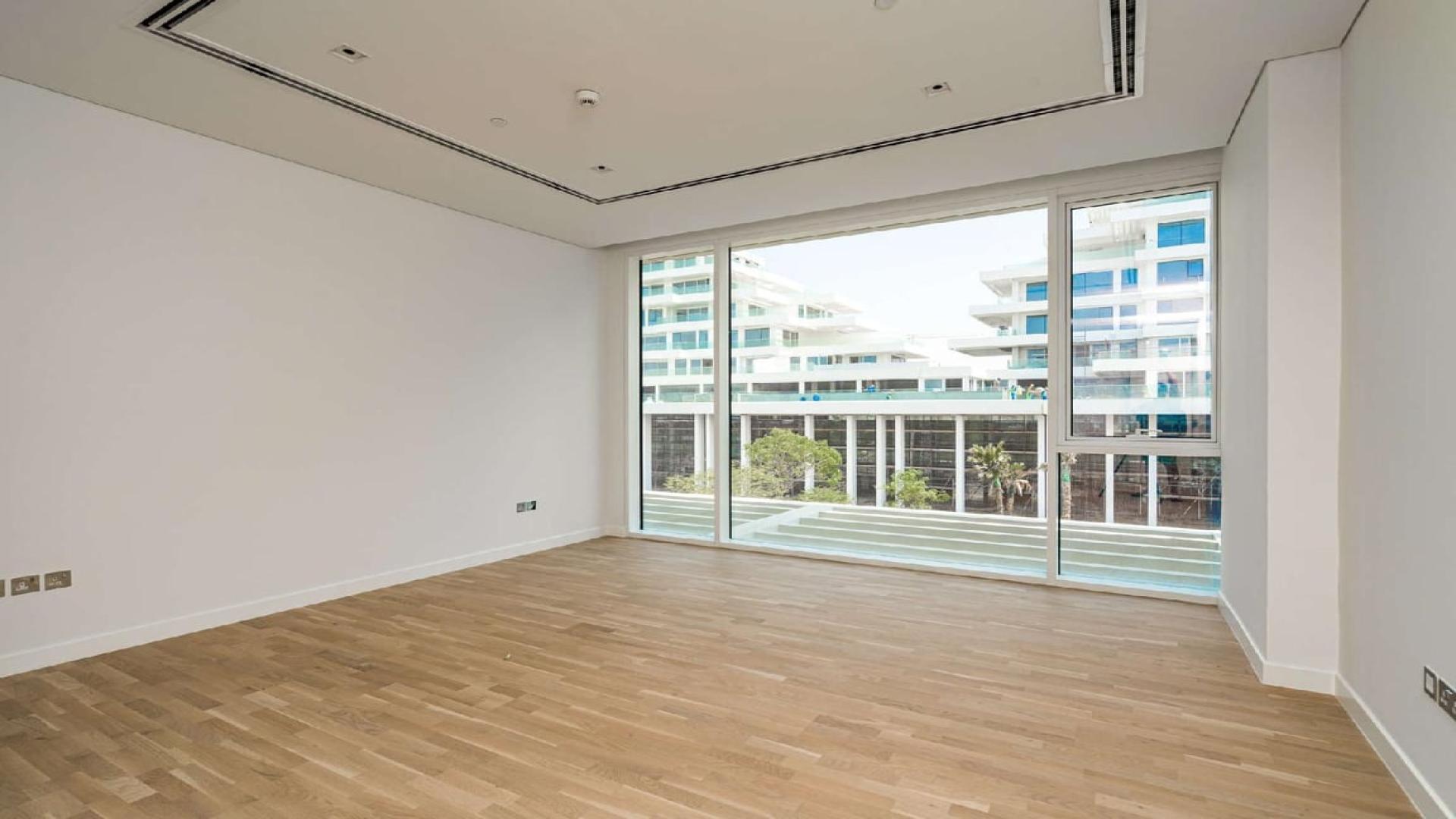 Empty room with wooden floor and large window in Ashjar apartment, Al Barari