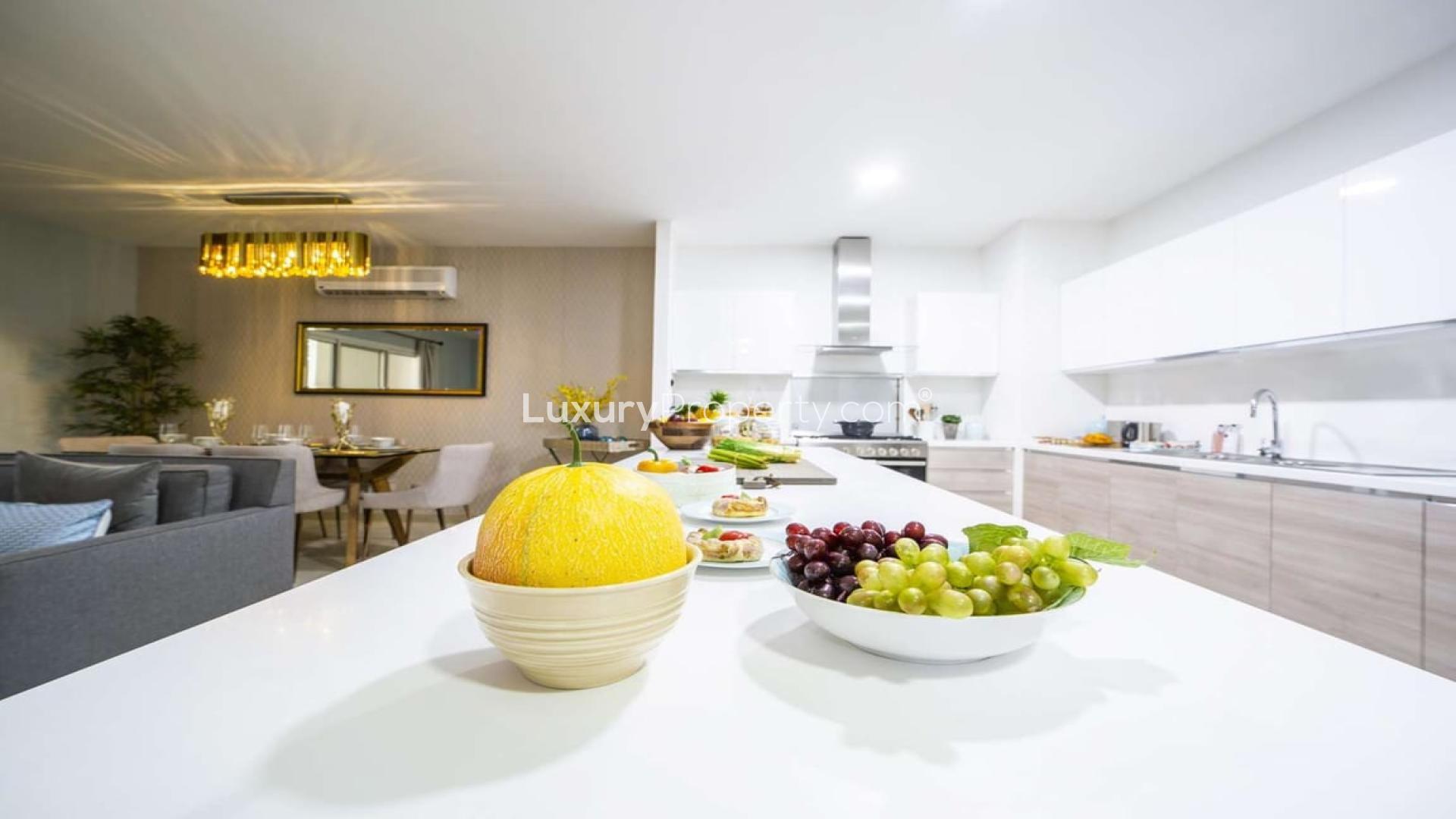 Modern kitchen in Al Andalus two-bedroom apartment with sleek white cabinets and spacious island