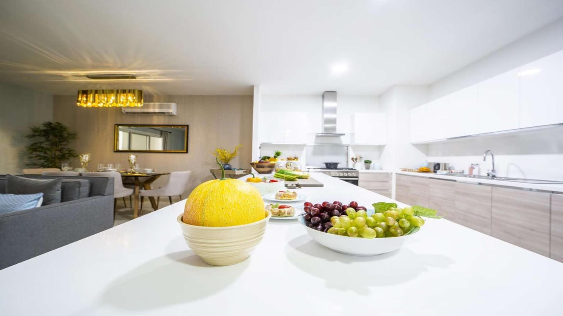Modern kitchen in Al Andalus two-bedroom apartment with sleek white cabinets and spacious island