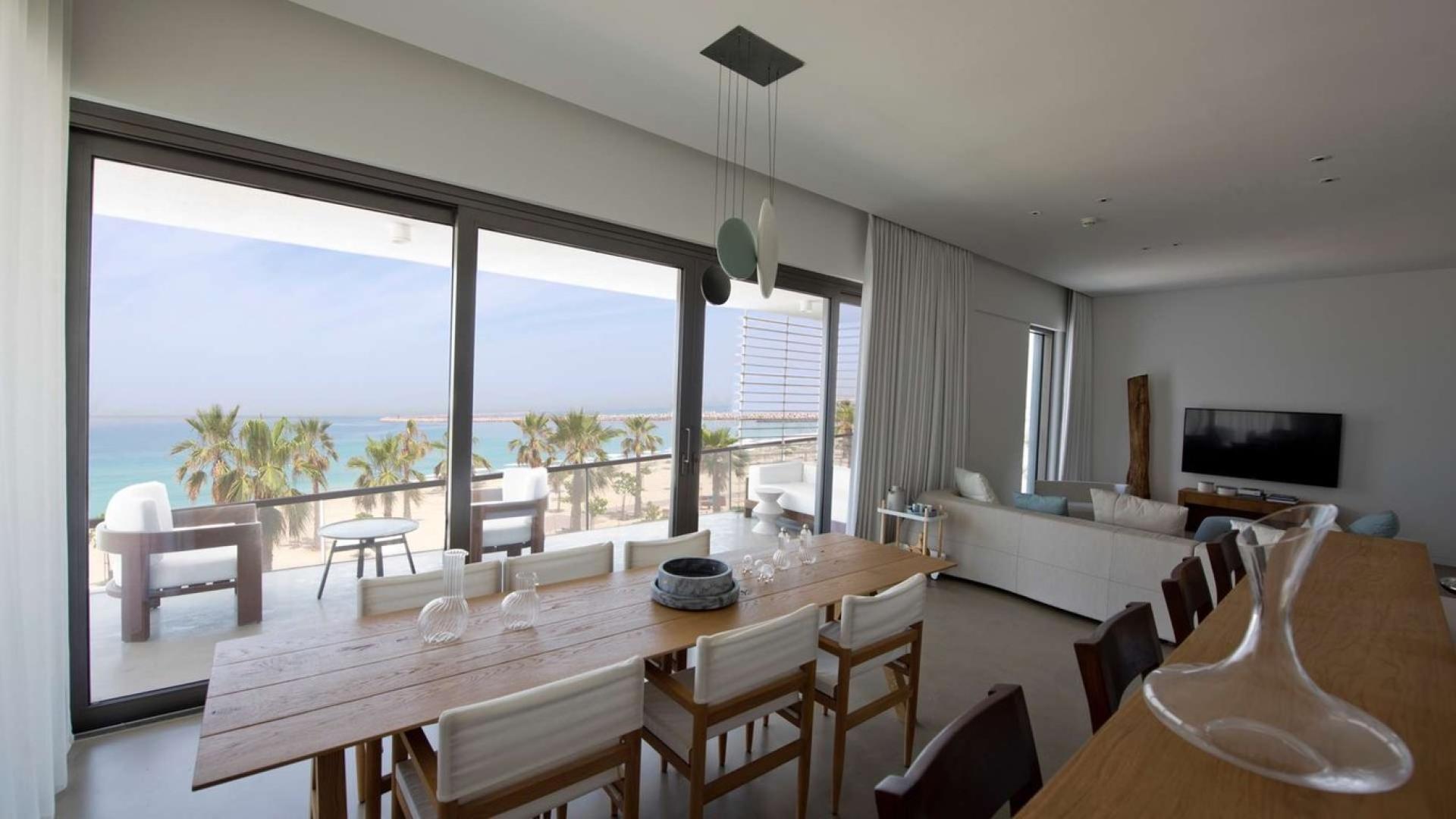 Outdoor pool area at Pearl Jumeirah apartment complex with lounge chairs and palm trees
