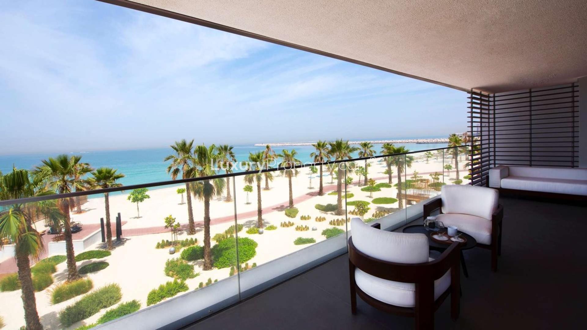 "Spacious living area with ocean view in Pearl Jumeirah apartment for sale.","Spacious Pearl Jumeirah apartment balcony with stunning beach view, ideal for family living.",Balcony view of beach and palm trees at apartment in Pearl Jumeirah, Dubai