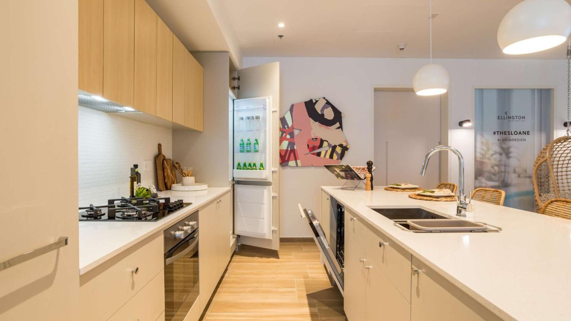 Modern kitchen in JVC apartment, featuring sleek countertops and open fridge, The Sloane