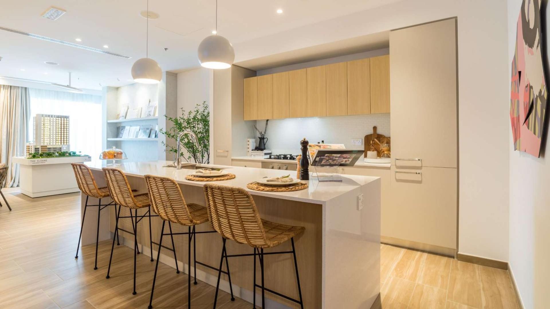 "Stylish dining area in 2-bedroom apartment, The Sloane, Jumeirah Village Circle, for sale.",Modern kitchen with island seating in JVC apartment for sale, The Sloane community