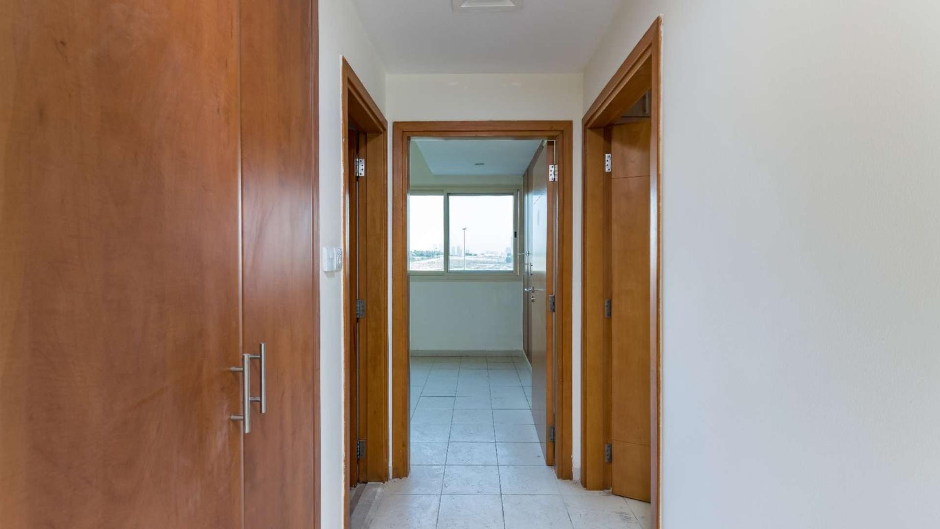 Empty living space in Al Alka apartment with tiled floor and open kitchen area