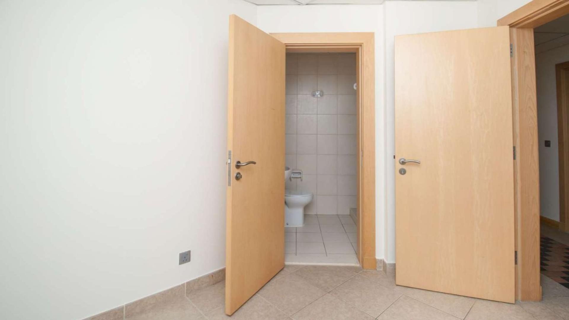 "Spacious living area in 2-bedroom Shoreline apartment, Palm Jumeirah, for sale.",Open bathroom door in 2-bedroom Shoreline Apartment, Palm Jumeirah, tiled floor, beige tones