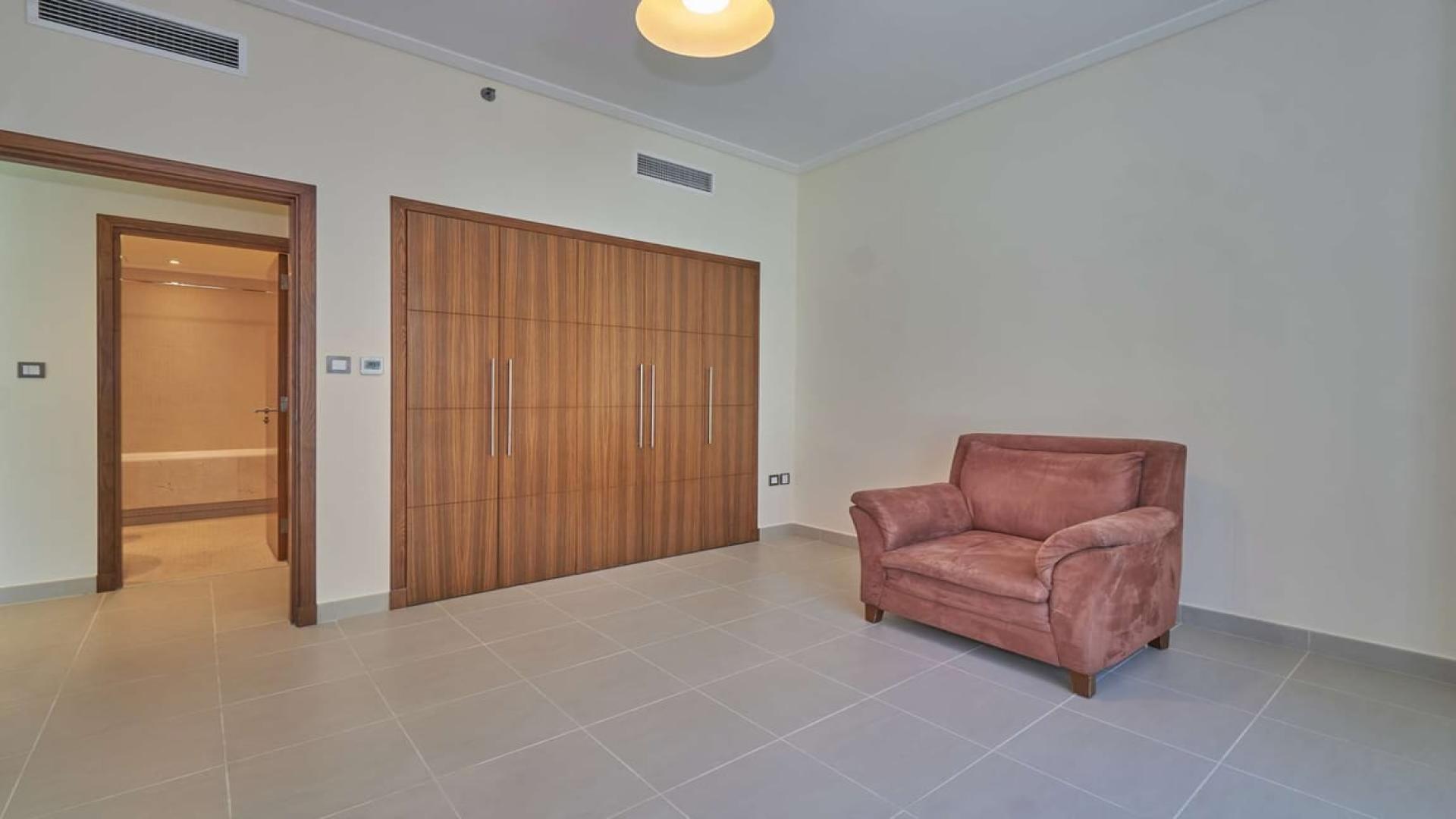 Empty room with built-in wardrobe and pink armchair in Dubai Marina apartment for sale