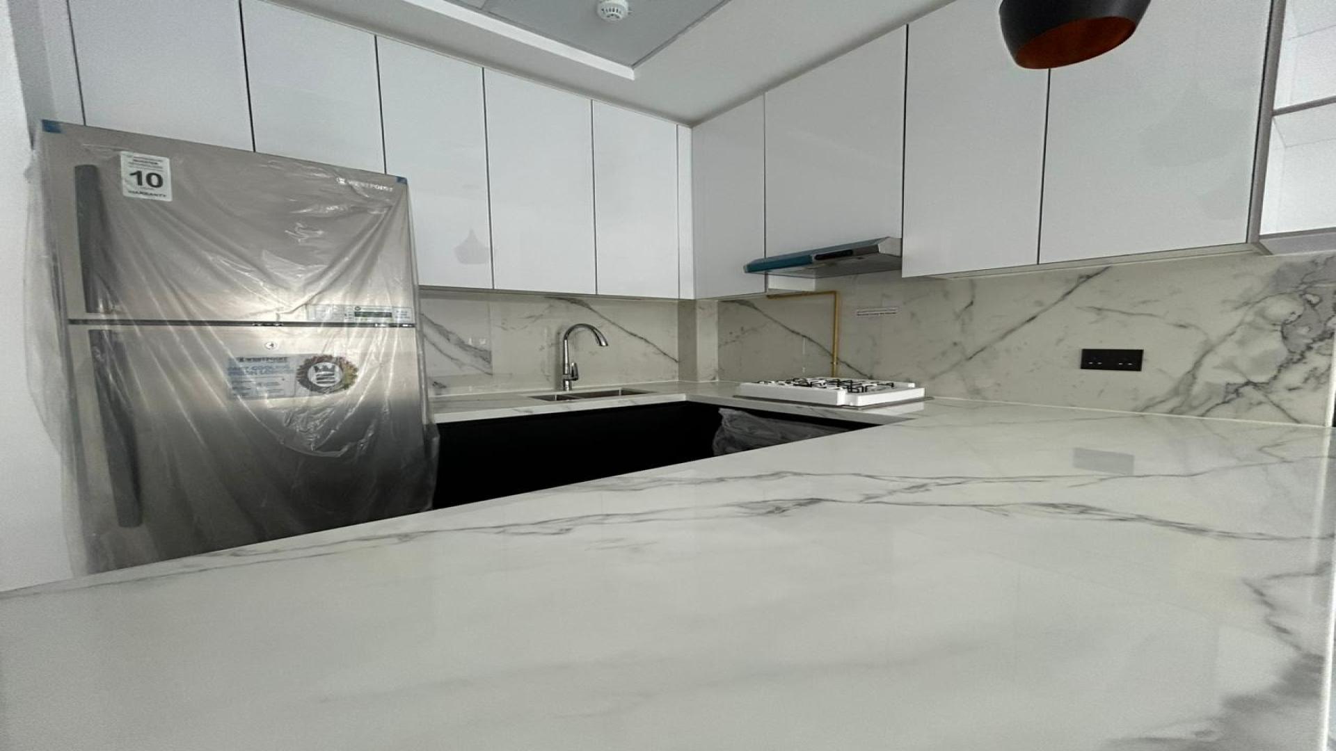 Modern open-plan living area in Arjan apartment with sleek flooring and kitchen view