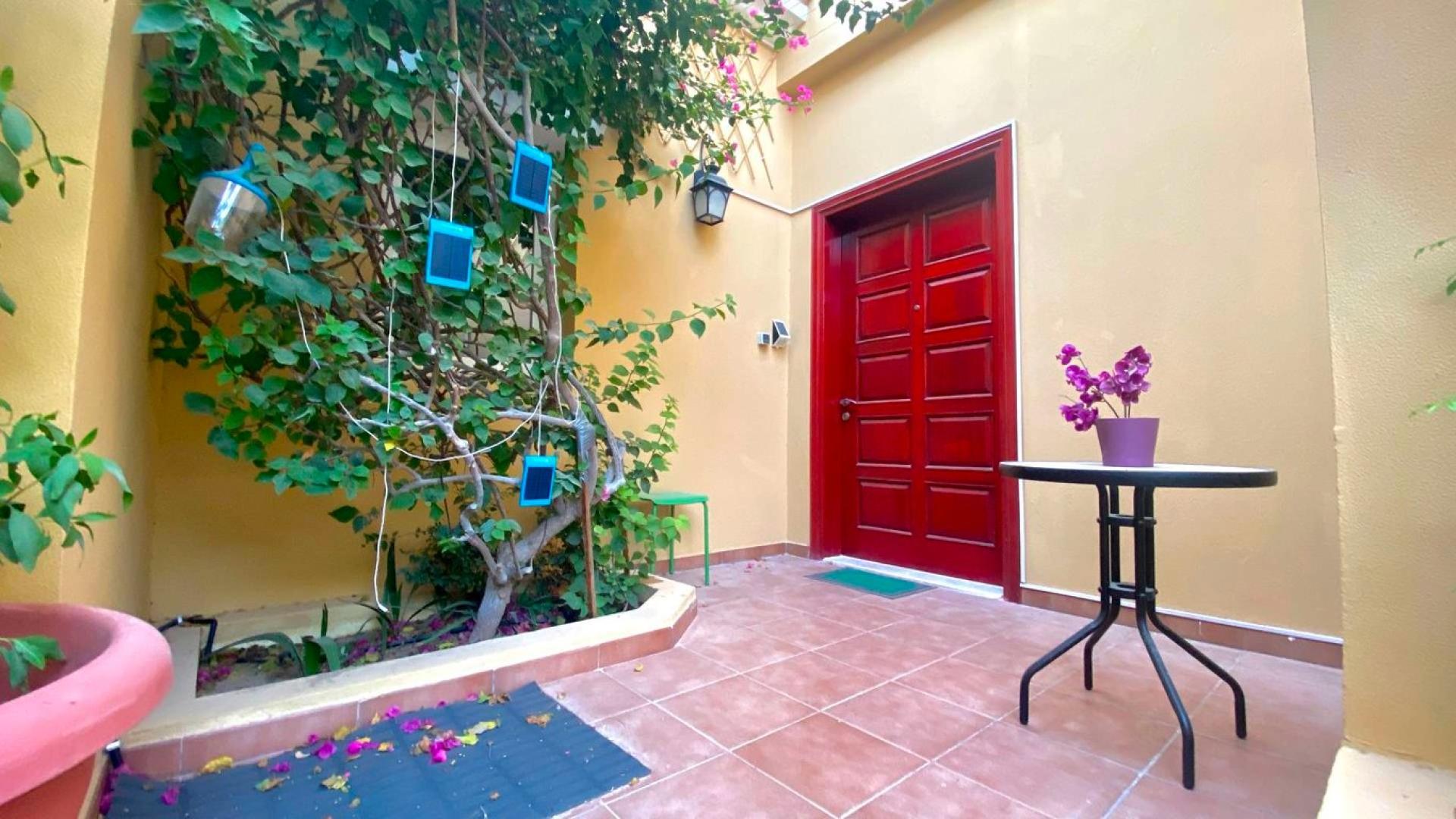 "Well-presented townhouse exterior with garage in Palmera, Arabian Ranches, for sale.",Front entrance of Palmera townhouse with red door and potted plants, Arabian Ranches