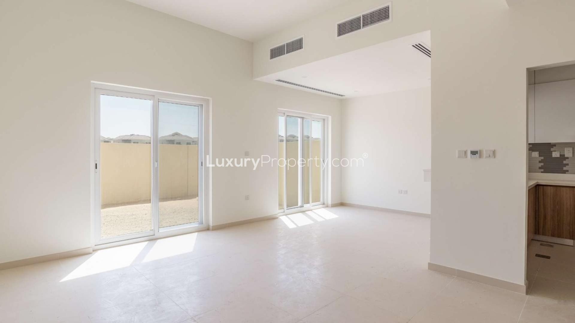 Carport view of Villanova townhouse with red car, Dubai Land, for sale