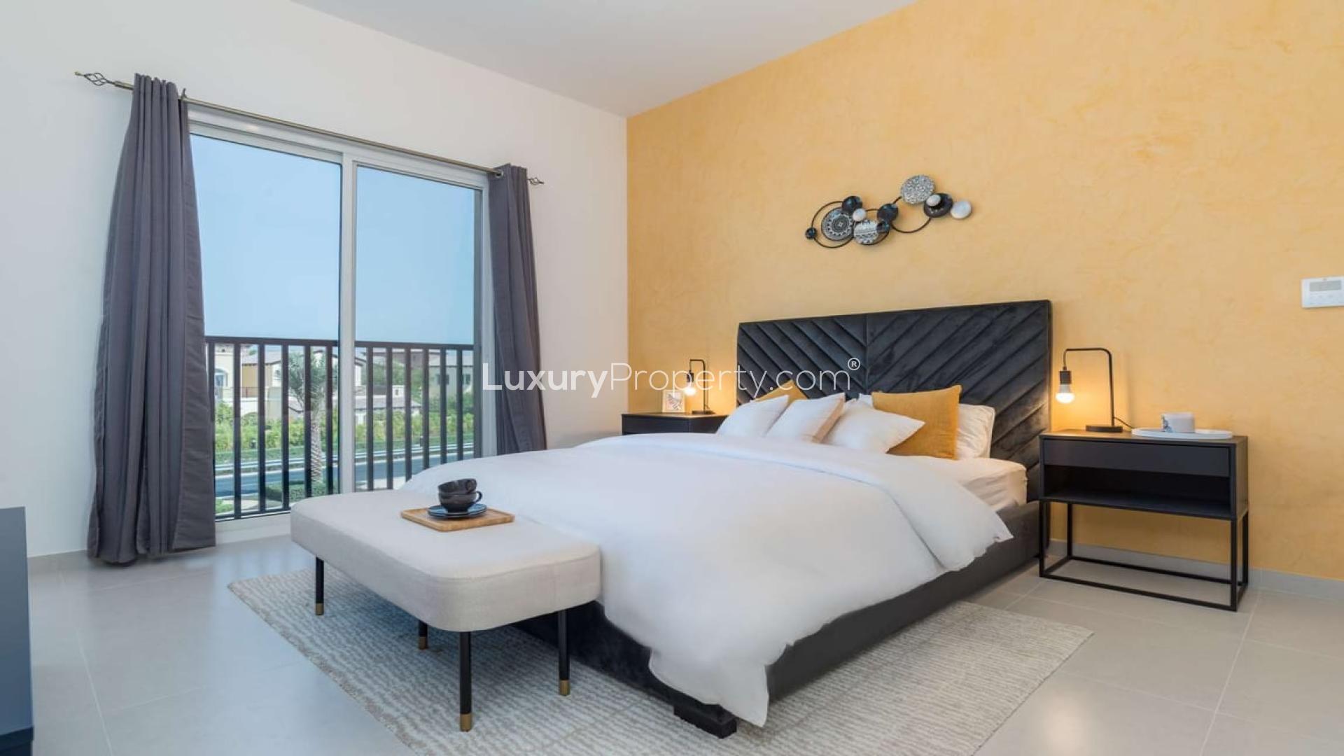 Luxury bedroom interior in Zafran Townhouses, Jumeirah Golf Estates, with modern decor and balcony view
