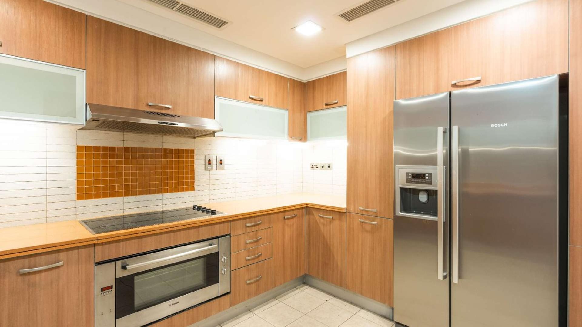 Modern kitchen in Palm Jumeirah townhouse, featuring sleek appliances and wooden cabinetry