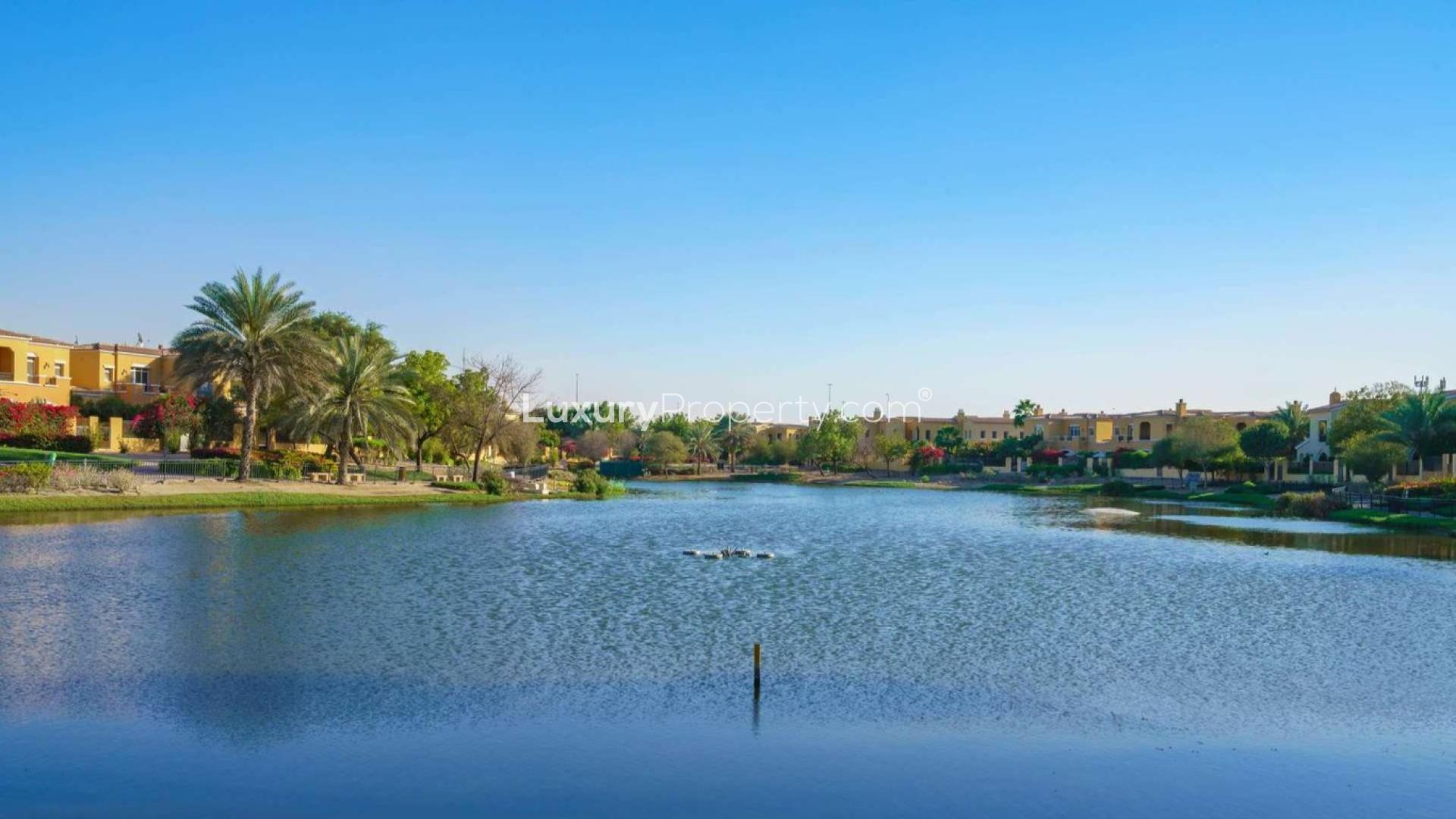 Living room in Arabian Ranches villa with modern decor and garden view through glass door
