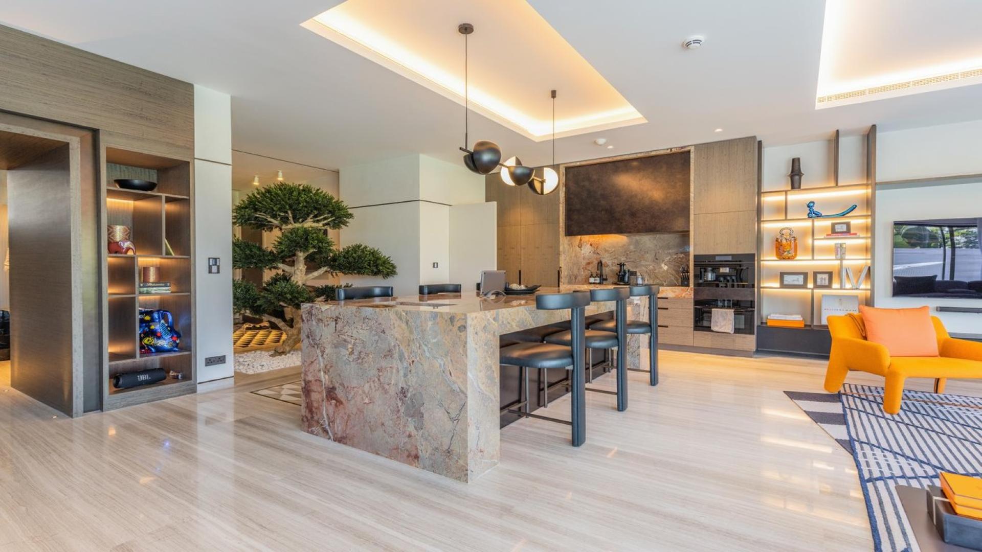 Luxurious outdoor seating by private pool in Emirates Hills villa, surrounded by lush greenery