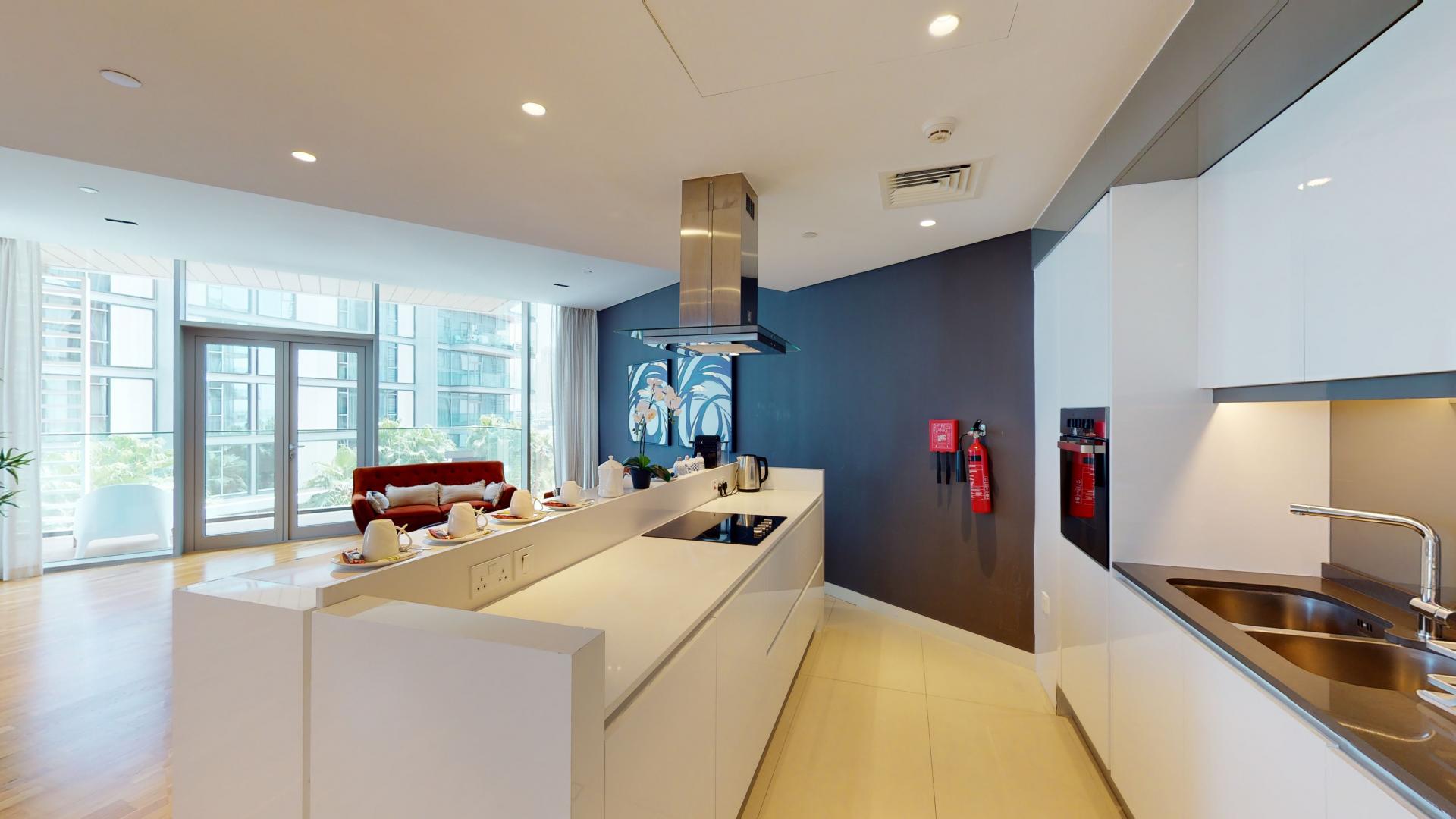 "Balcony view of furnished apartment in Bluewaters Residences, lush greenery and modern architecture.",Modern kitchen and living area in furnished Bluewaters apartment for rent, LP15236