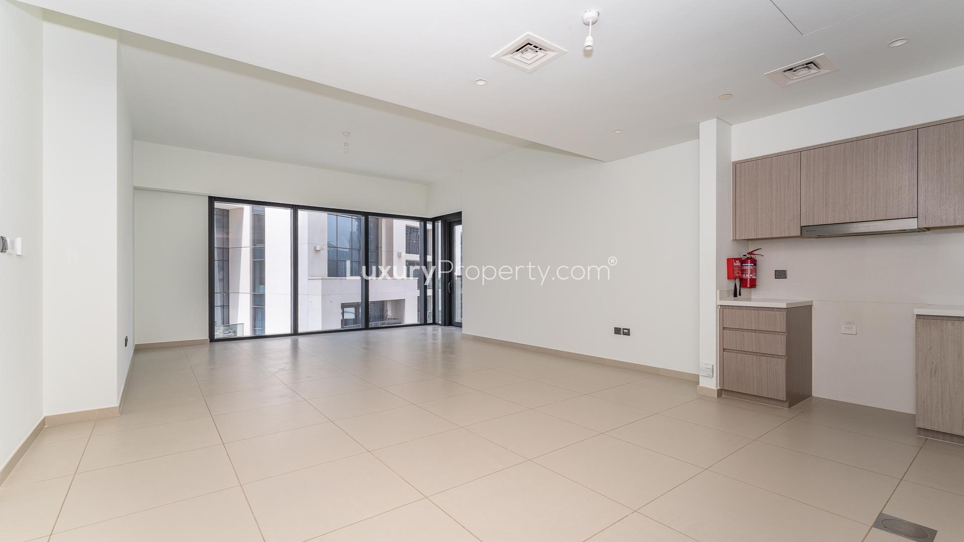 Empty living area in Act Towers apartment, Downtown Dubai, with modern kitchen and tiled flooring