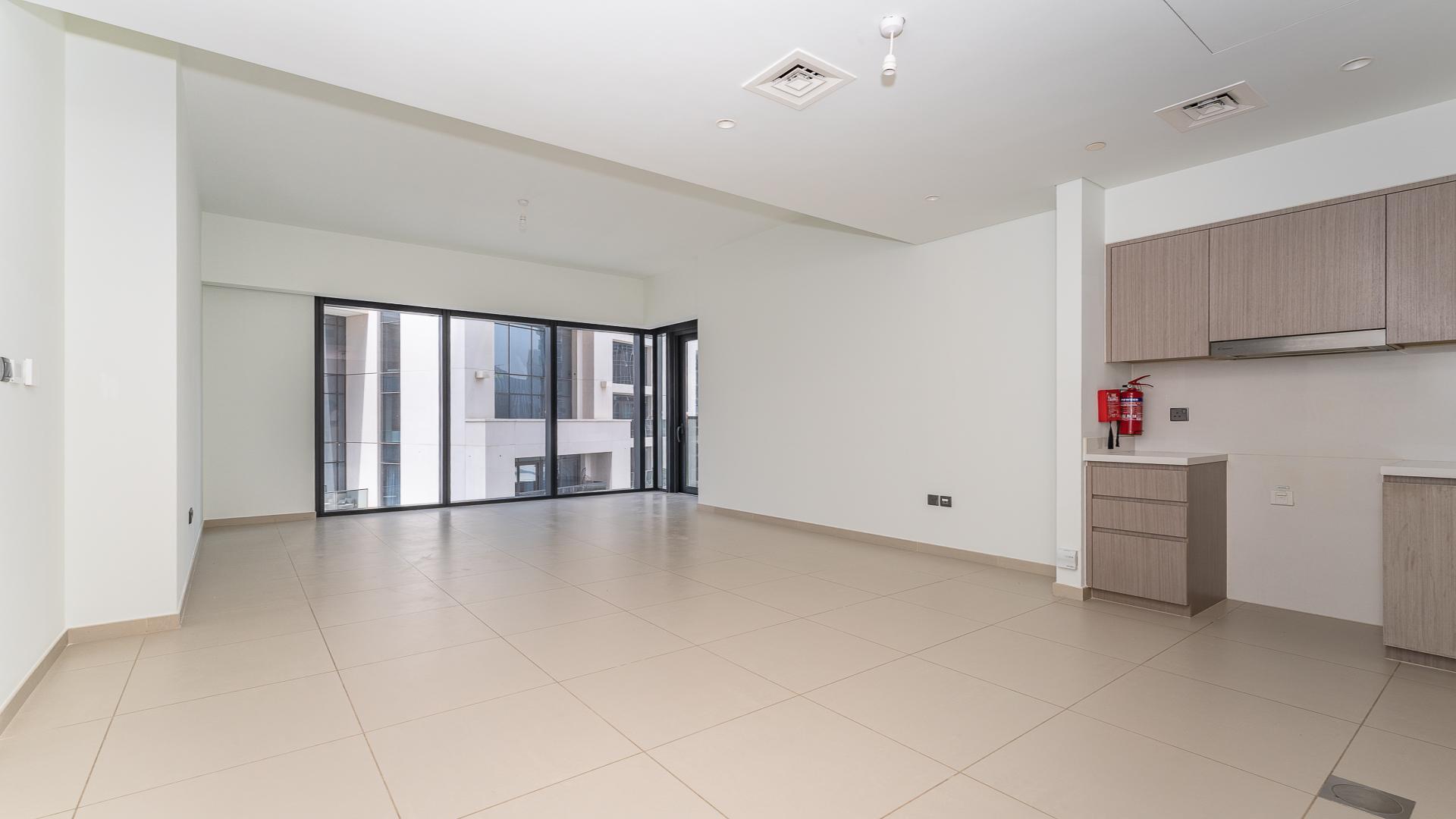 Empty living area in Act Towers apartment, Downtown Dubai, with modern kitchen and tiled flooring