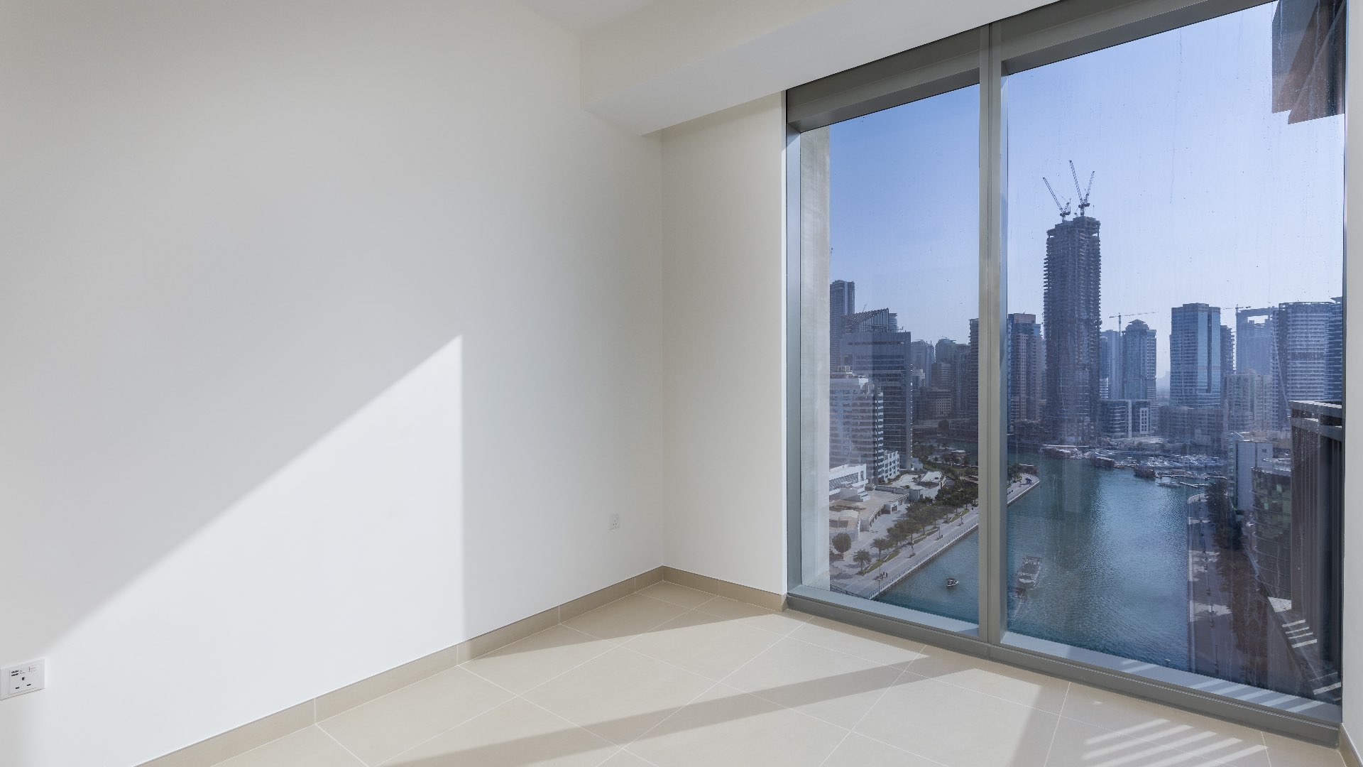 Empty room with large window overlooking Dubai Marina skyline and waterfront views