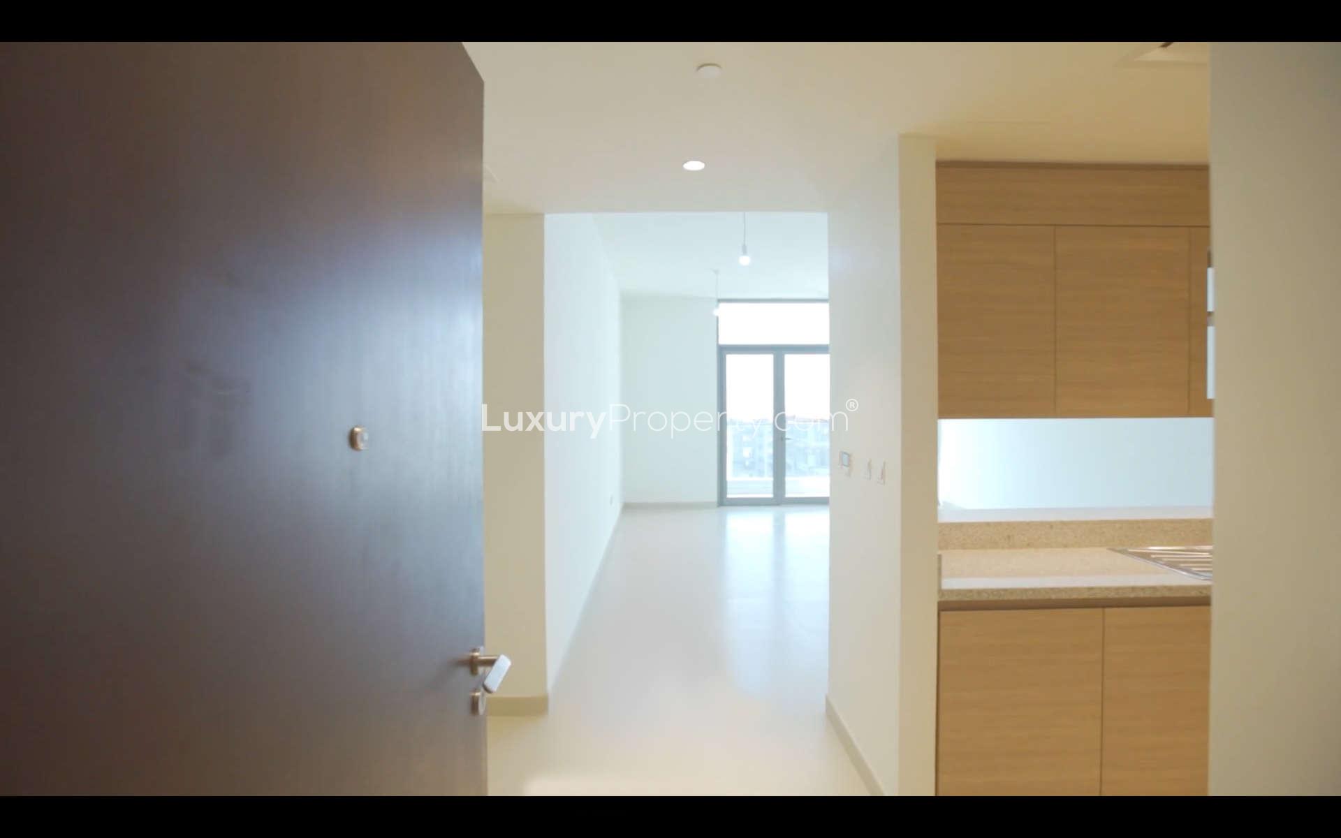 Empty room in Acacia Park Heights apartment, Dubai Hills Estate, with white walls and doorway