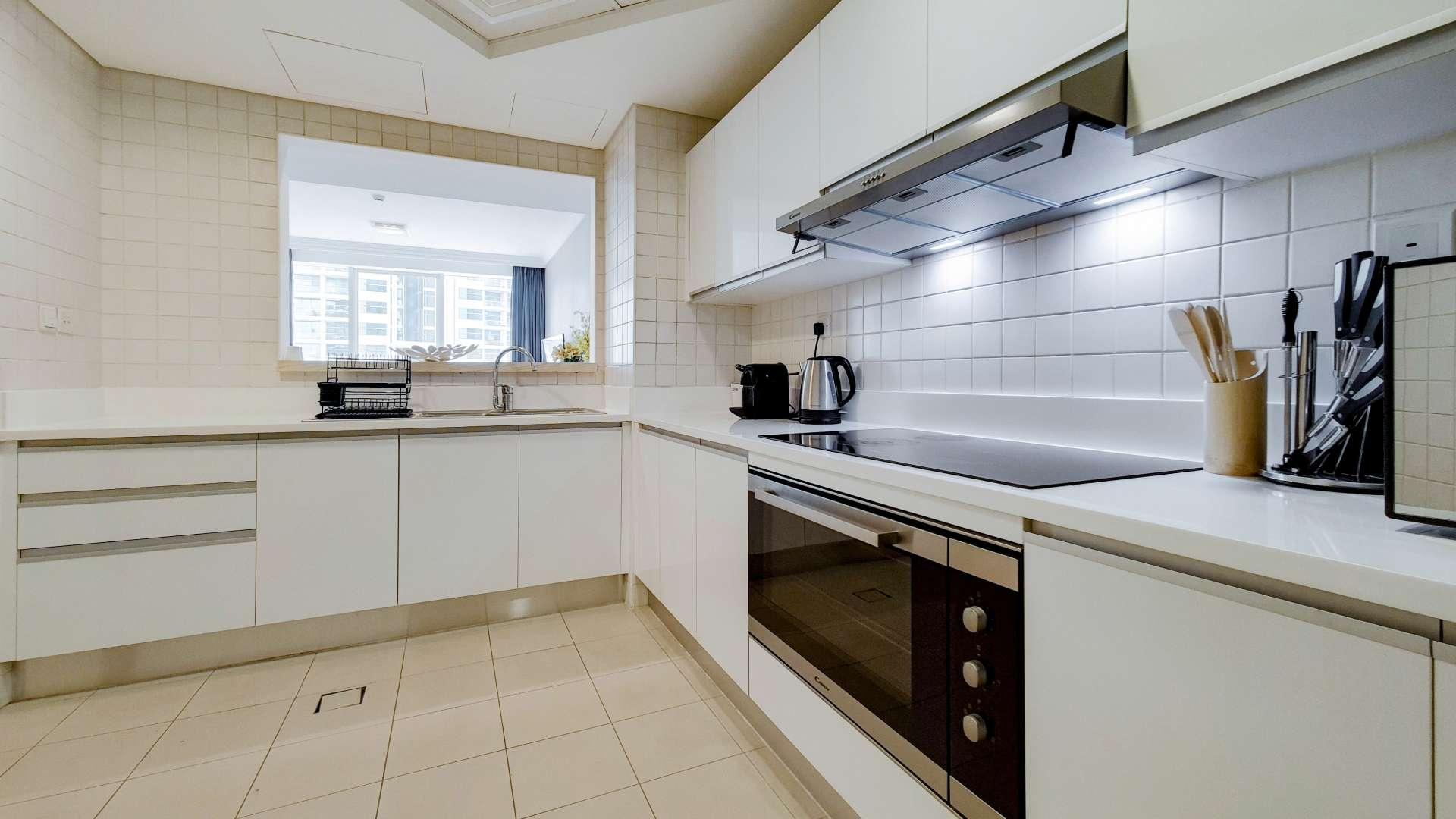 Modern kitchen in Al Bateen Residence apartment, Jumeirah Beach, with sleek white cabinetry
