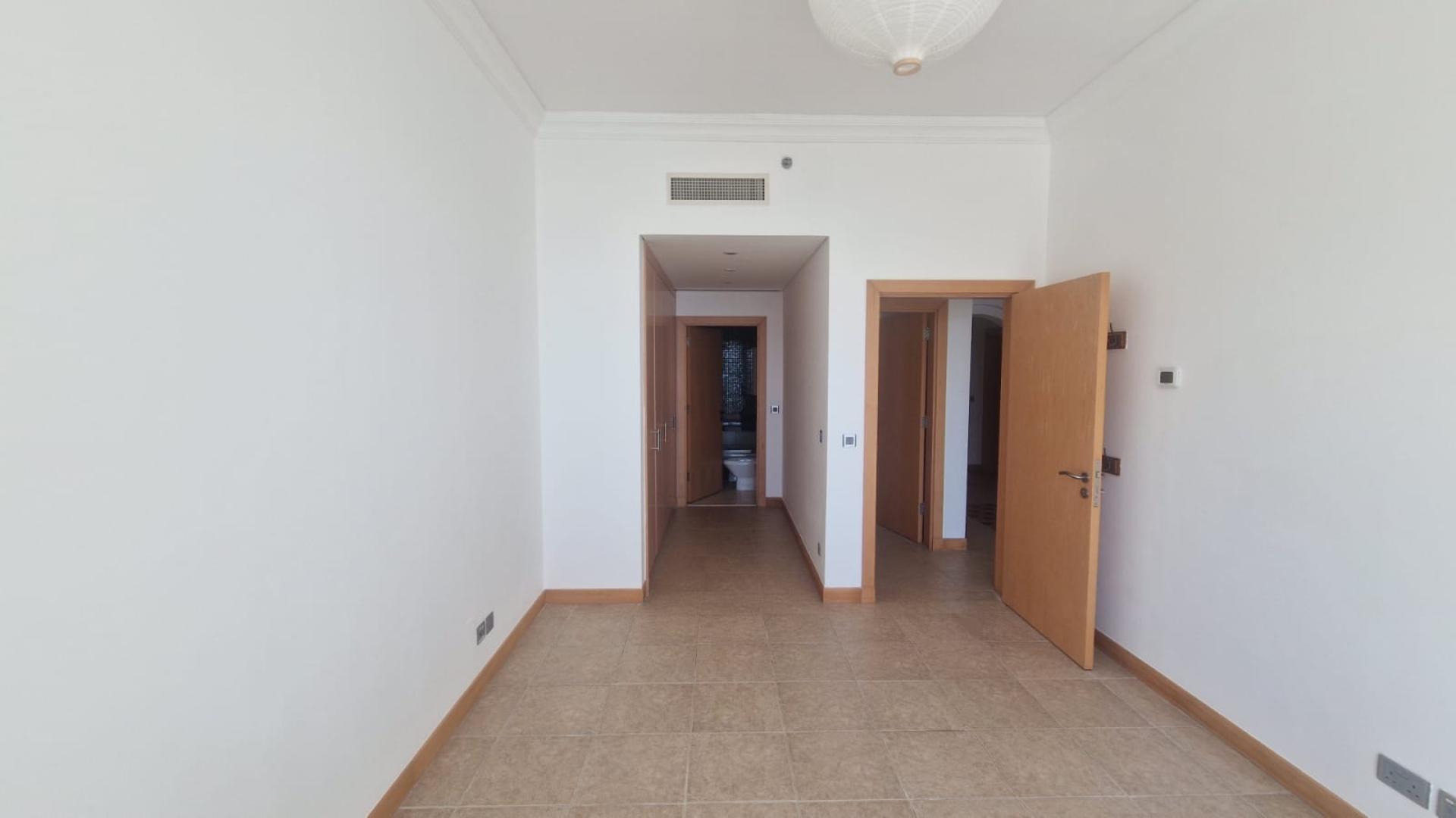 "Beachfront view from Shoreline Apartments, Palm Jumeirah, with lush greenery and sea vista.",Empty room view in Shoreline Apartments, Palm Jumeirah, featuring tiled floors and open doors