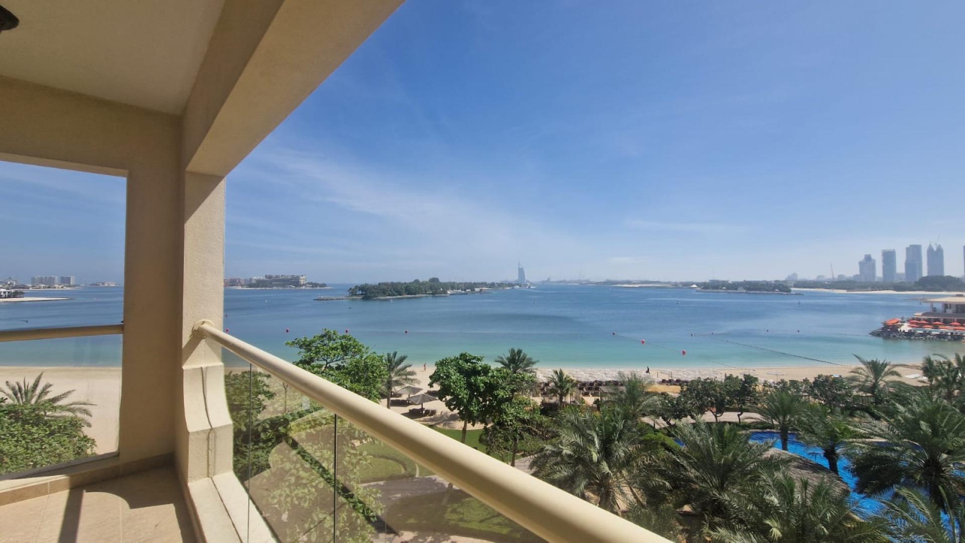 "Beachfront view from Shoreline Apartments, Palm Jumeirah, with lush greenery and sea vista.",Balcony view of Palm Jumeirah shoreline from Shoreline Apartments, LP48822 rental listing