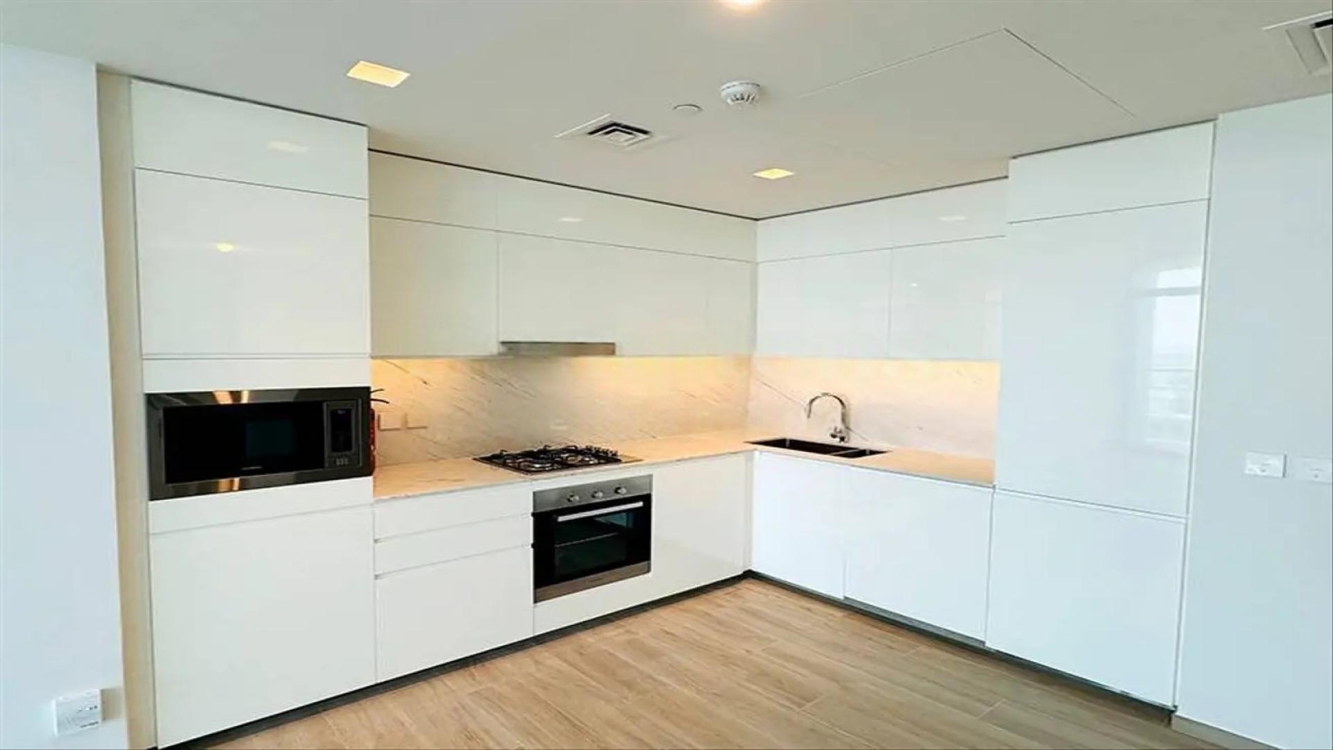 Modern kitchen in Dubai Creek Harbour apartment, featuring sleek white cabinets and appliances
