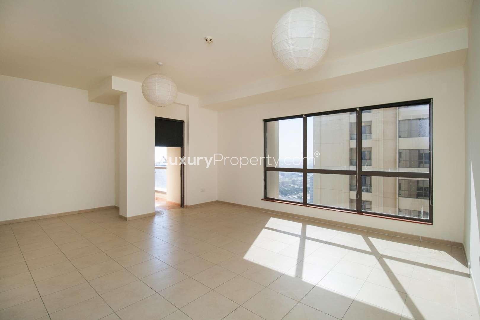 "Exterior view of Amwaj 4, JBR apartment building with landscaped entrance and modern architecture.",Empty living room with large windows, natural light, and tiled floor in Amwaj 4 apartment