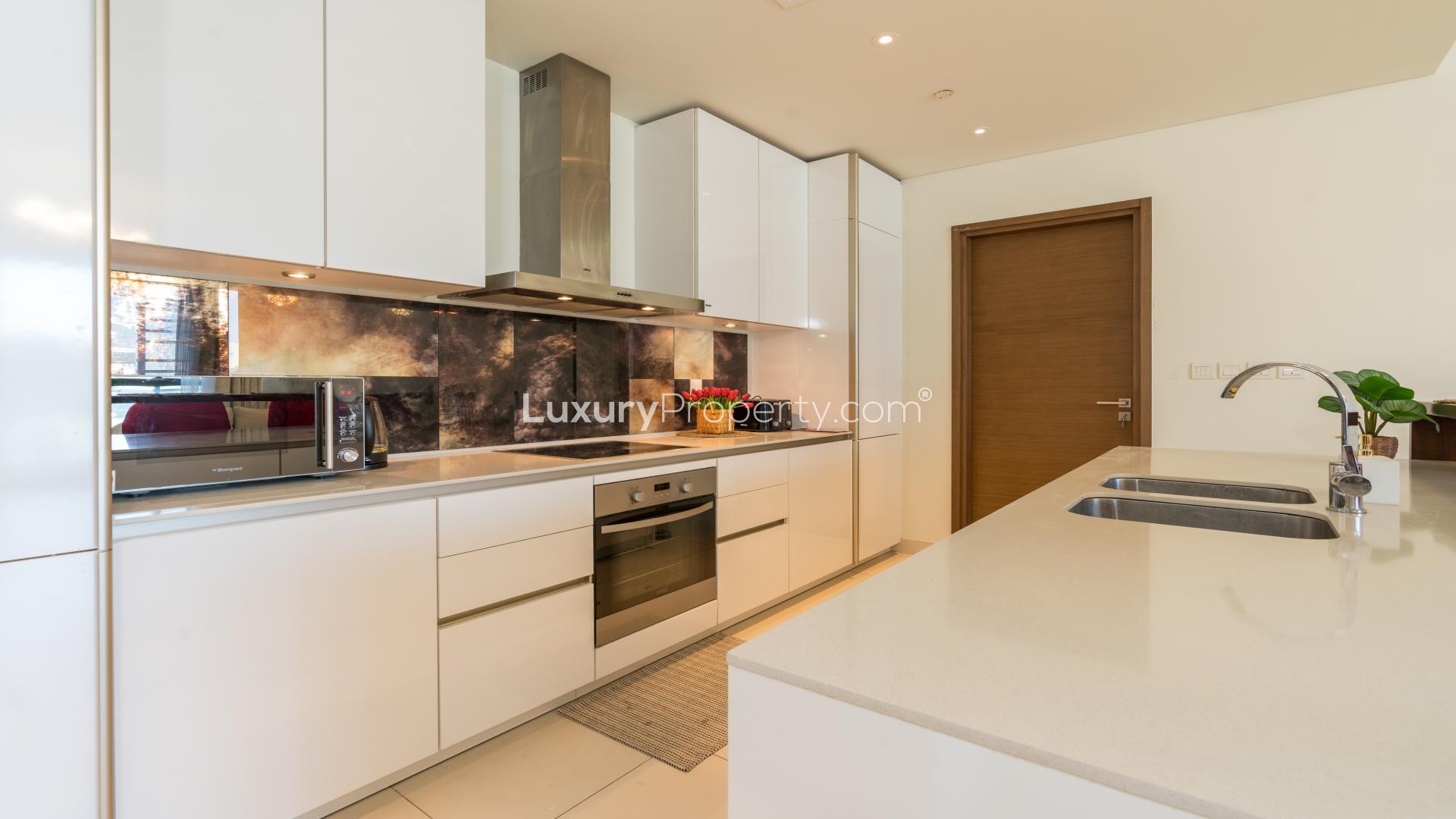 Modern kitchen in City Walk apartment with sleek design and vibrant red bar stools