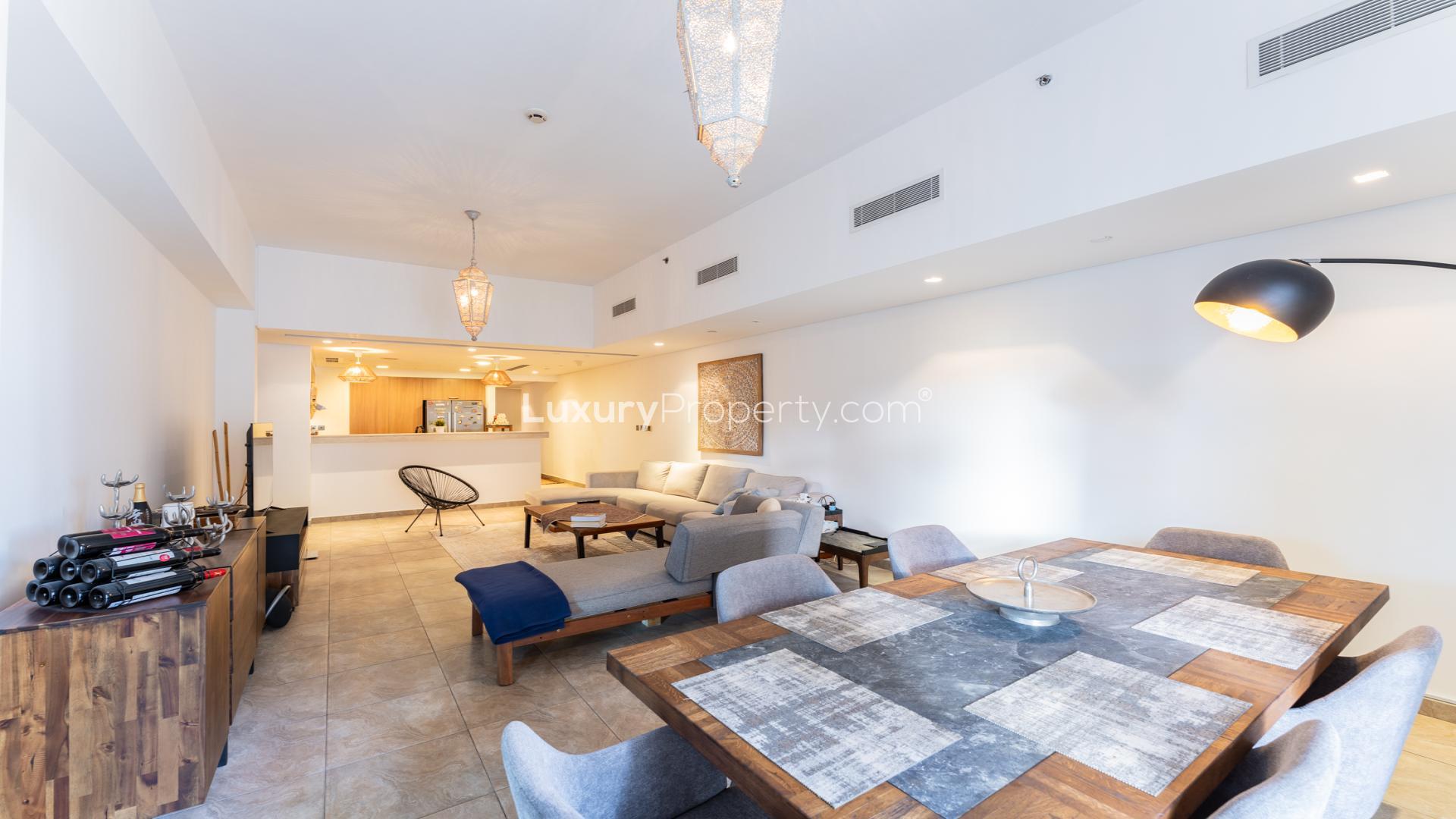 "Spacious terrace with outdoor seating in Palm Jumeirah apartment, overlooking lush gardens and pool.",Modern open-plan living area in Palm Jumeirah apartment, featuring elegant dining and lounge spaces
