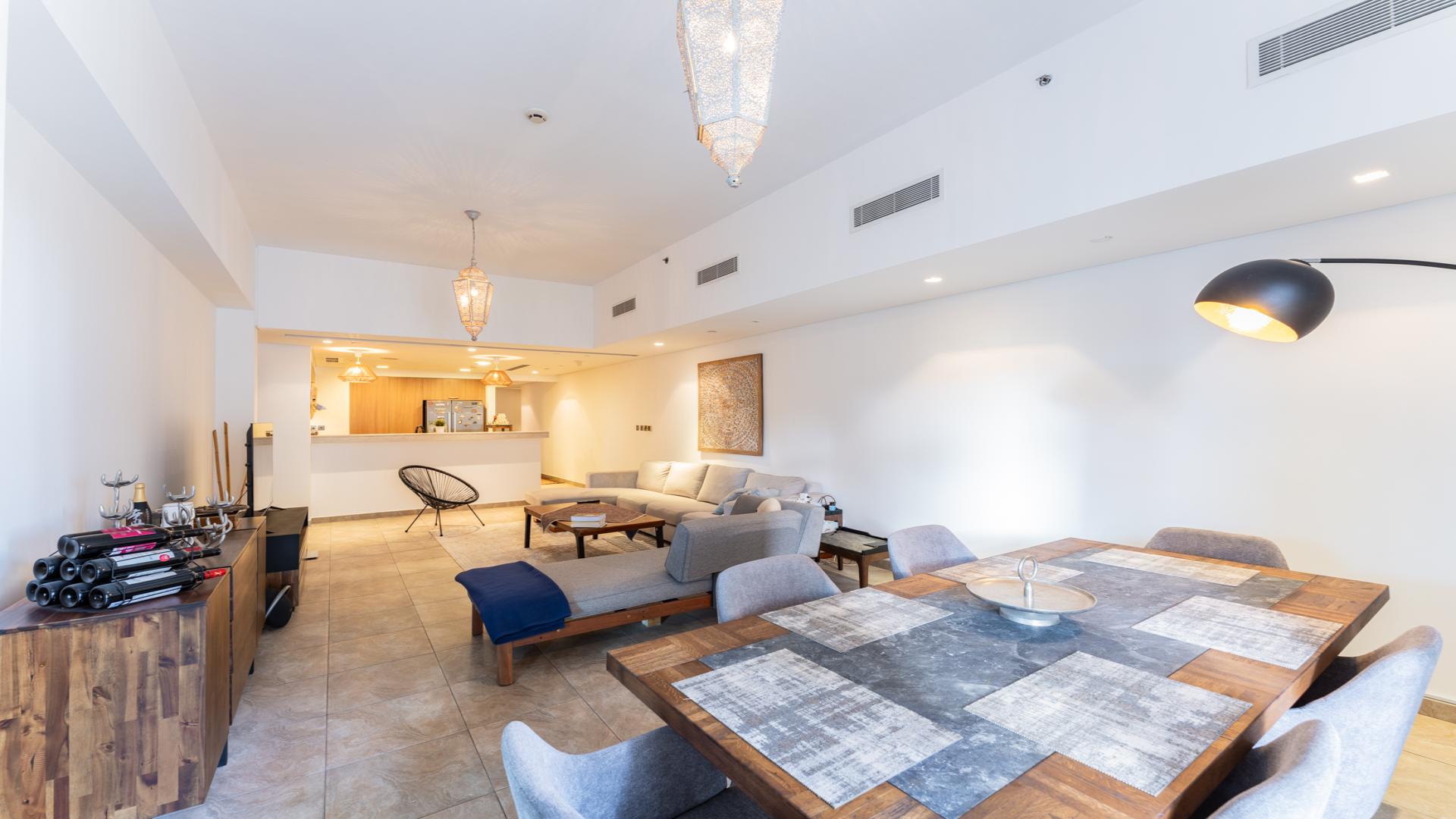 "Spacious terrace with outdoor seating in Palm Jumeirah apartment, overlooking lush gardens and pool.",Modern open-plan living area in Palm Jumeirah apartment, featuring elegant dining and lounge spaces