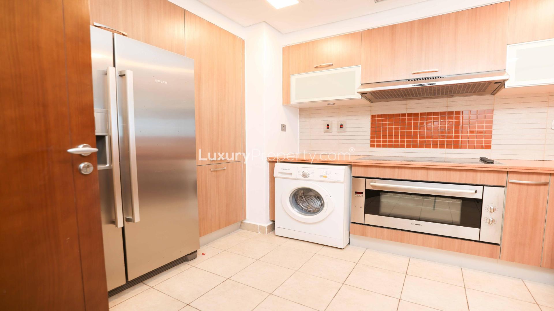 Modern kitchen in Palm Jumeirah apartment with stainless steel appliances and wood cabinetry